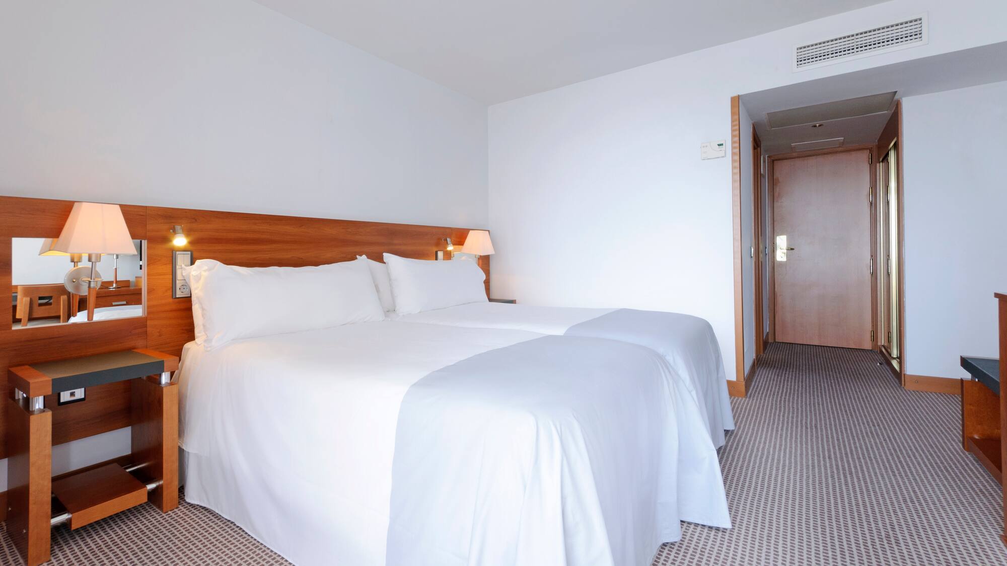 a bed with white sheets and a wood headboard in a hotel room