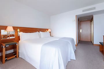 a bed with white sheets and a wood headboard in a hotel room
