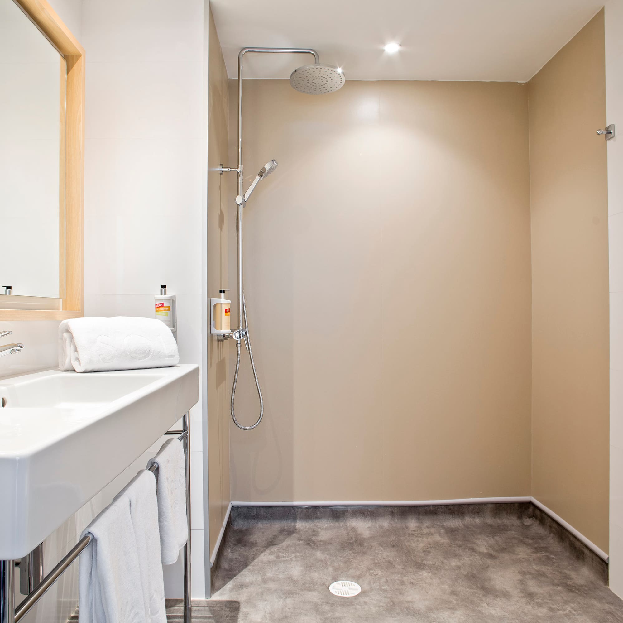 Modern bathroom with white sink, mirror, and open walk-in shower.