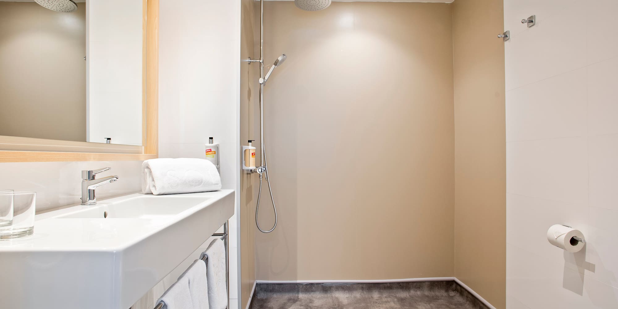 Modern bathroom with white sink, mirror, and open walk-in shower.