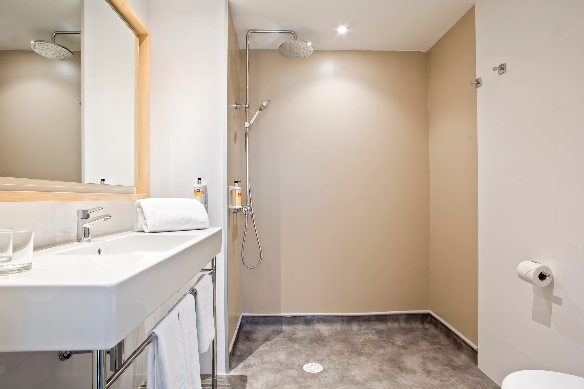 Modern bathroom with white sink, mirror, and open walk-in shower.