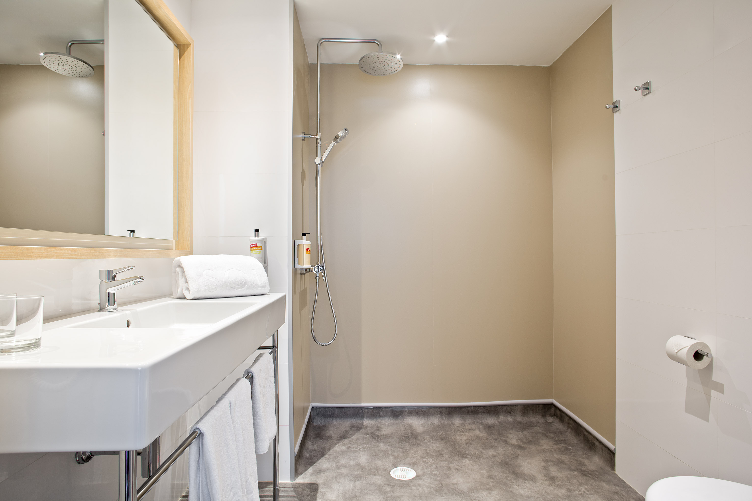 Modern bathroom with white sink, mirror, and open walk-in shower.