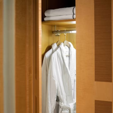a closet with white bathrobes and towels