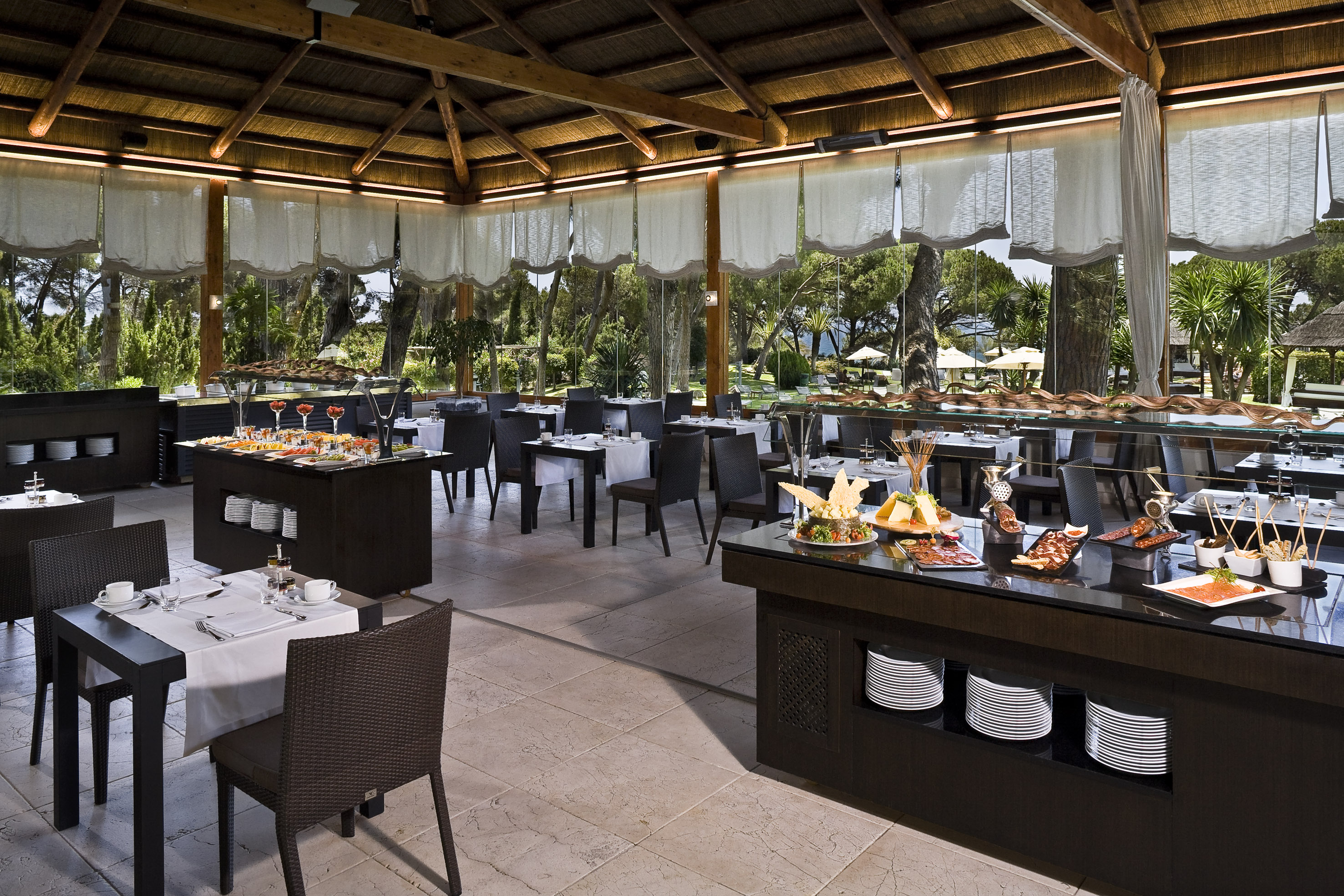 Resort dining room with buffet, tables, and panoramic garden views.