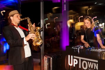 A man plays a saxophone beside a woman creating music.