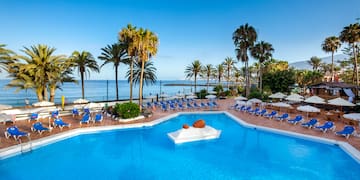 a pool with chairs and umbrellas by the water