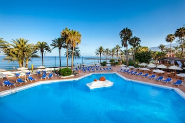 a pool with chairs and umbrellas by the water