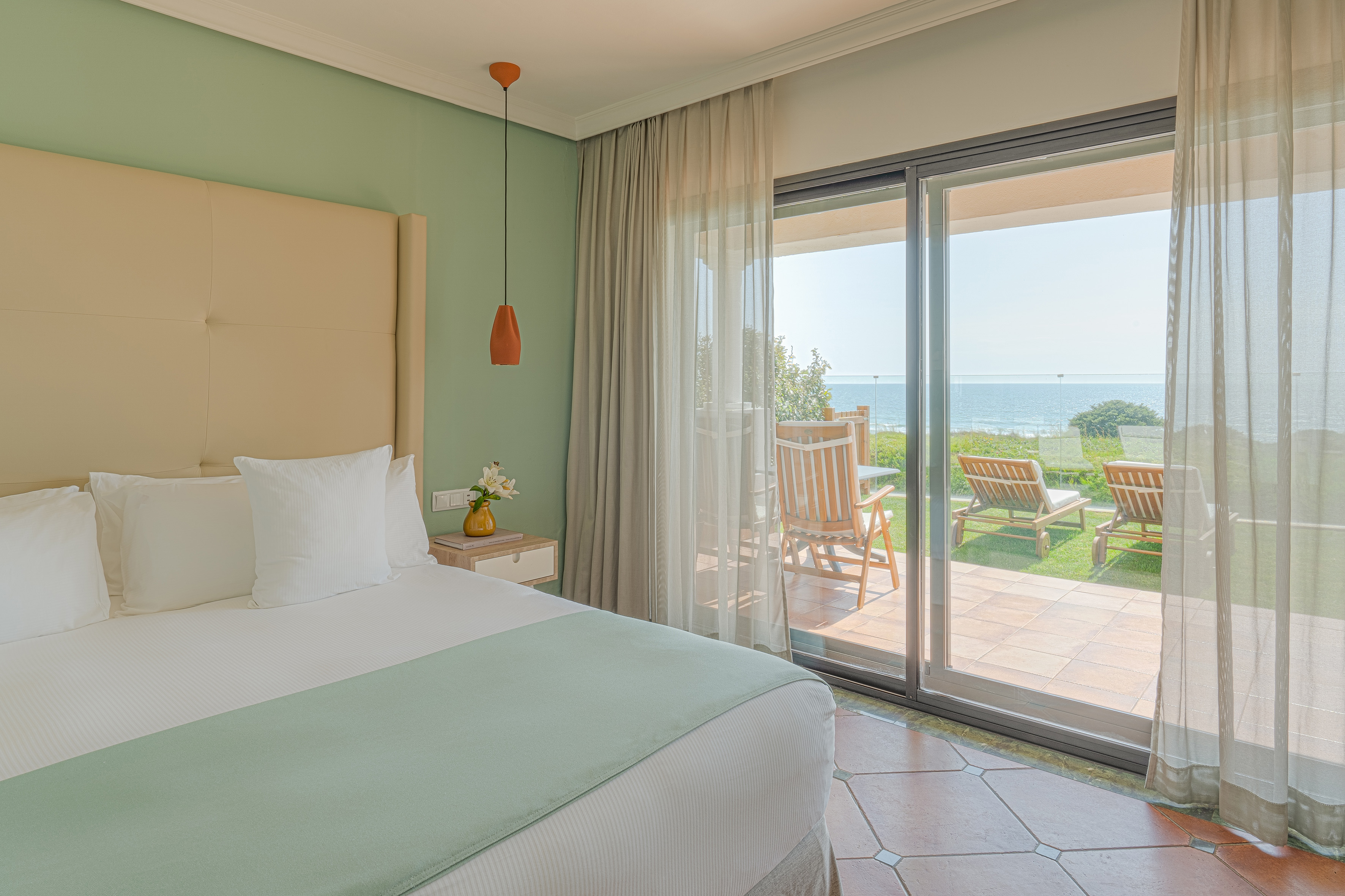 Beachfront hotel bedroom with ocean view and patio access.