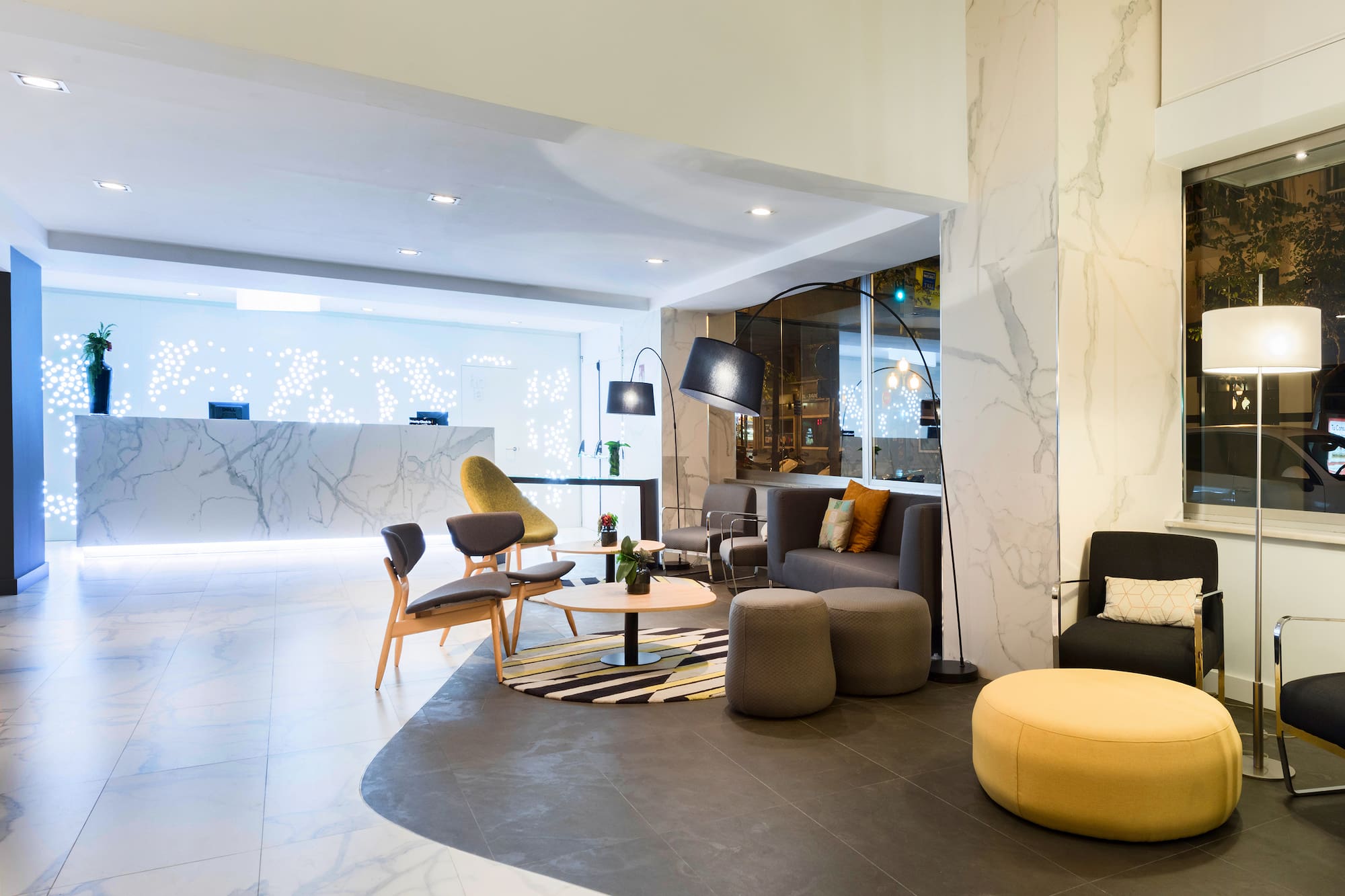 Modern hotel lobby with marble reception, lounge seating, and contemporary decor.