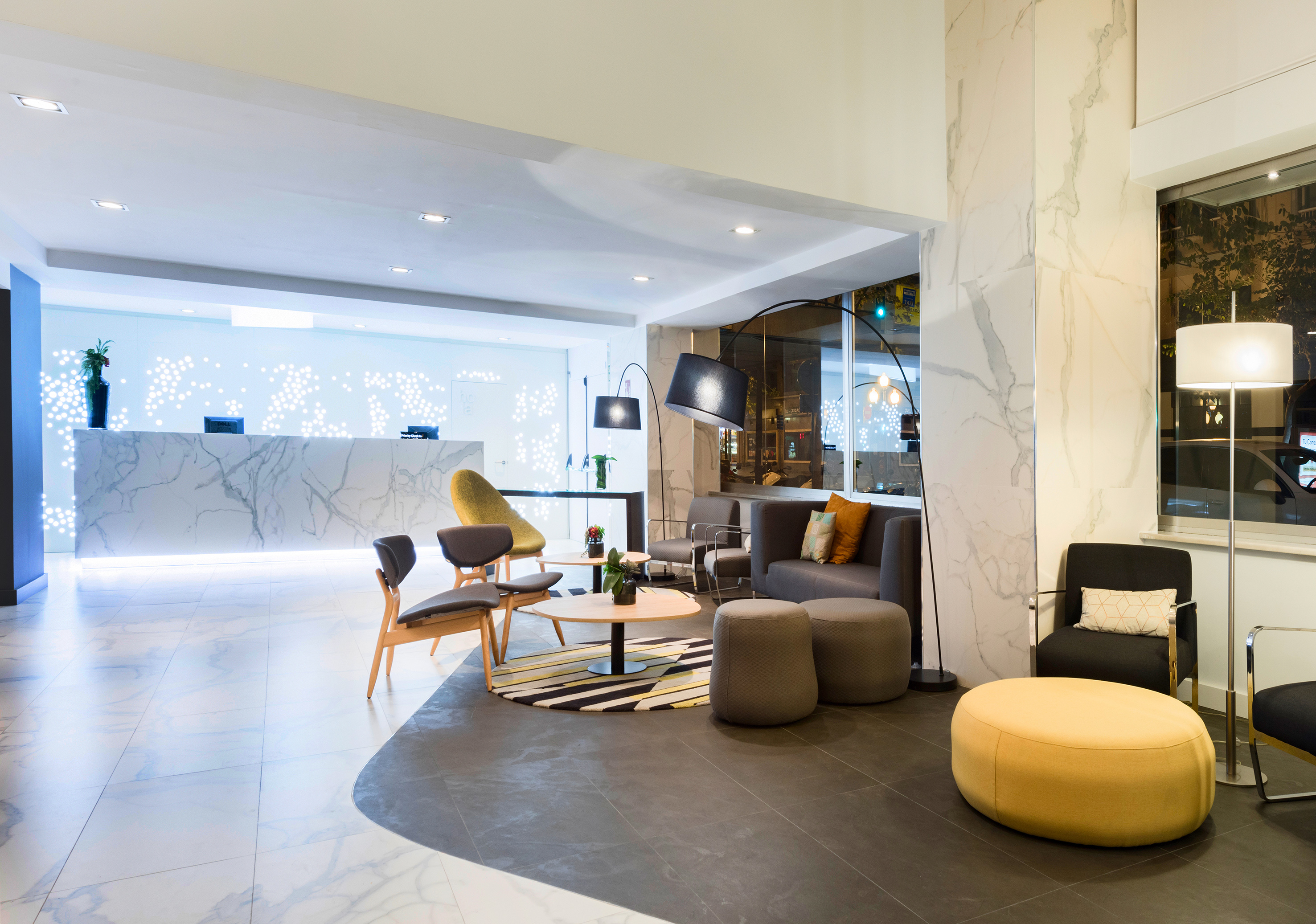 Modern hotel lobby with marble reception, lounge seating, and contemporary decor.