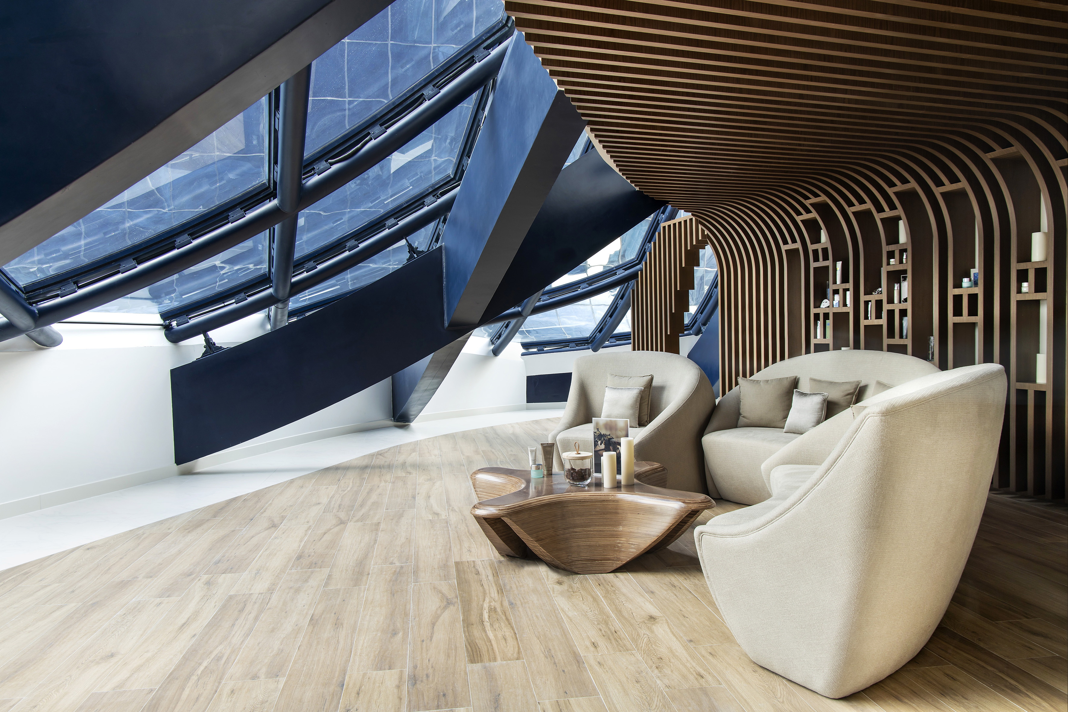 Modern lounge with architectural skylight, cozy seating, and wood slat walls.