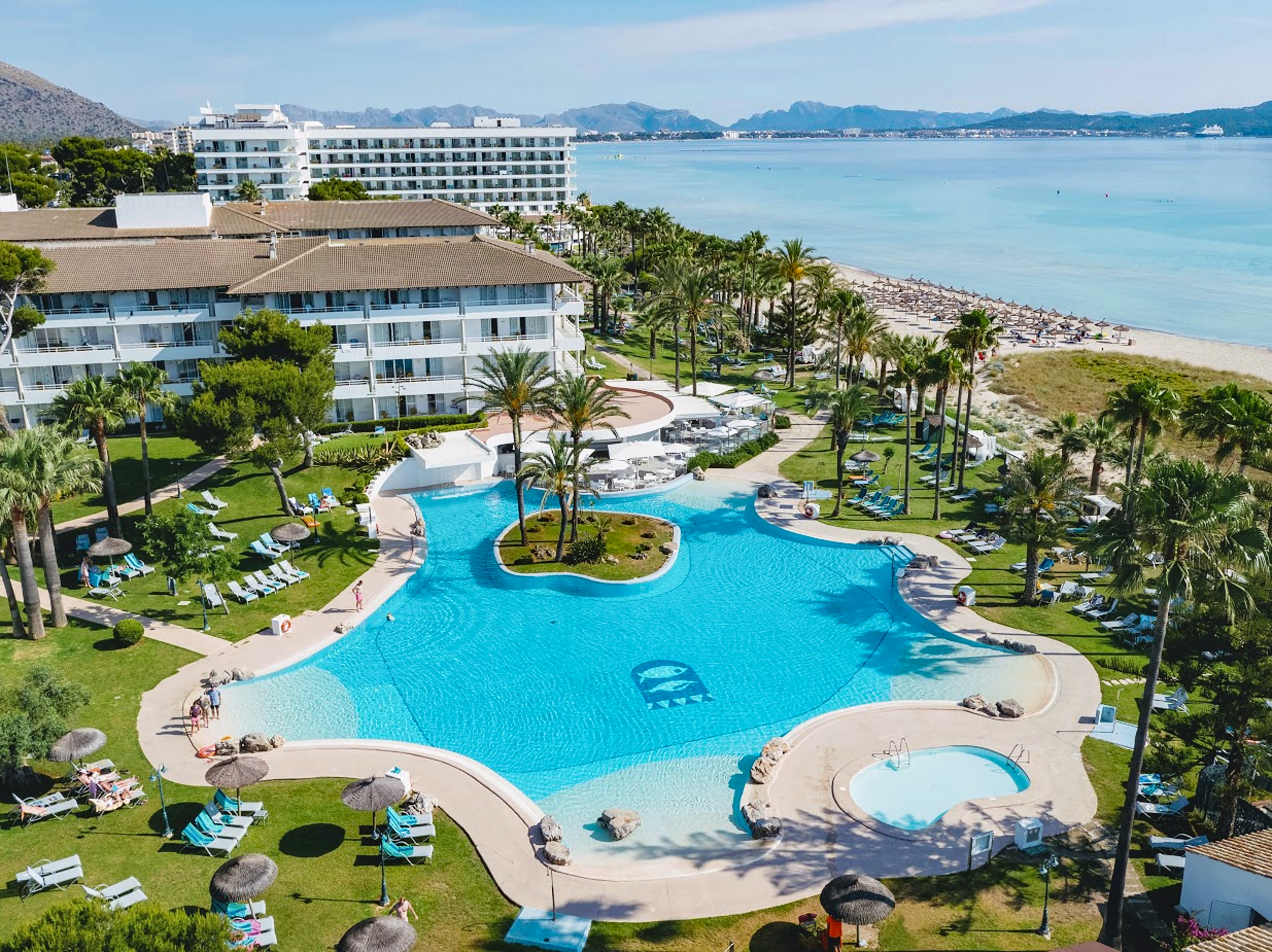 a swimming pool with palm trees and a beach - Verfrissende zwembaden - Playa Esperanza Resort Affiliated by Meliá, Mallorca