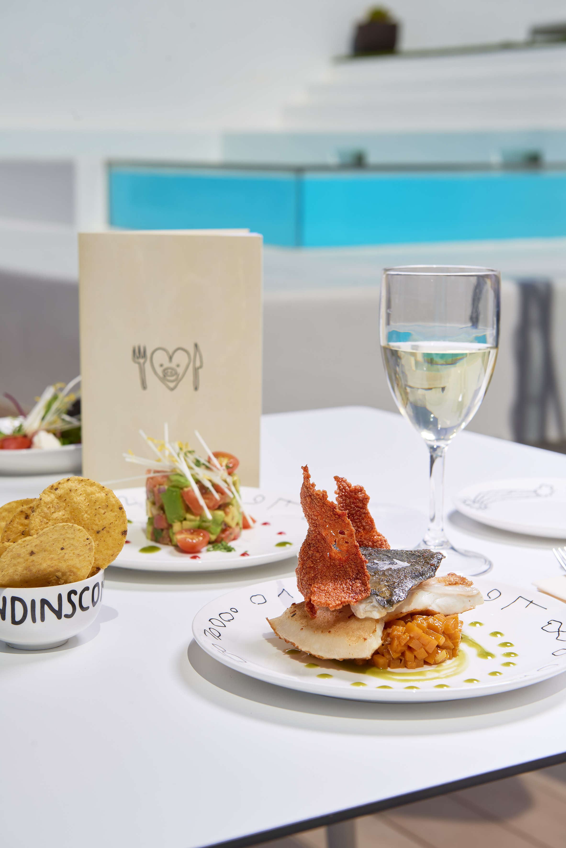 Gourmet fish meal and avocado tartare with white wine at a modern restaurant.