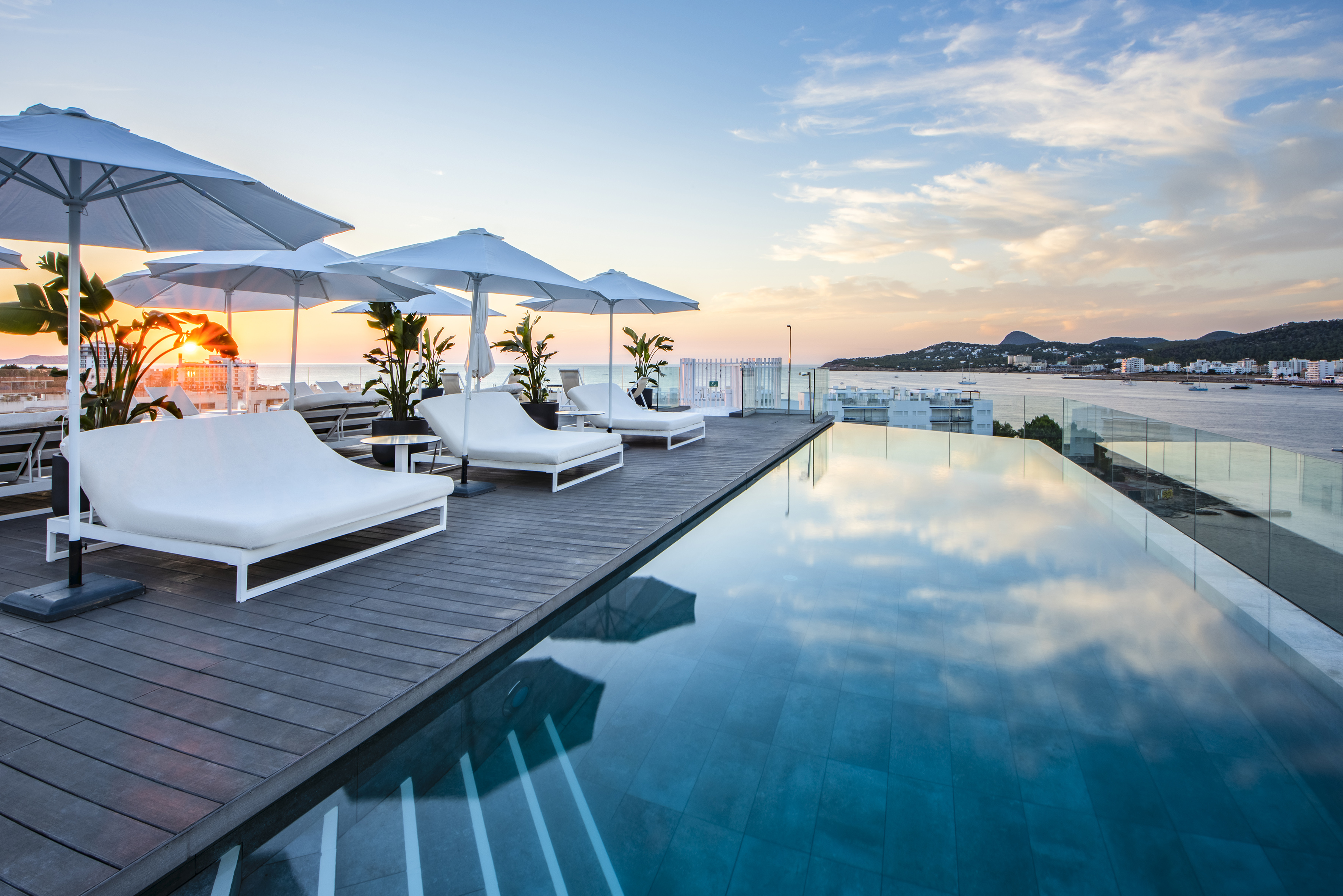 a pool with chairs and umbrellas by the water