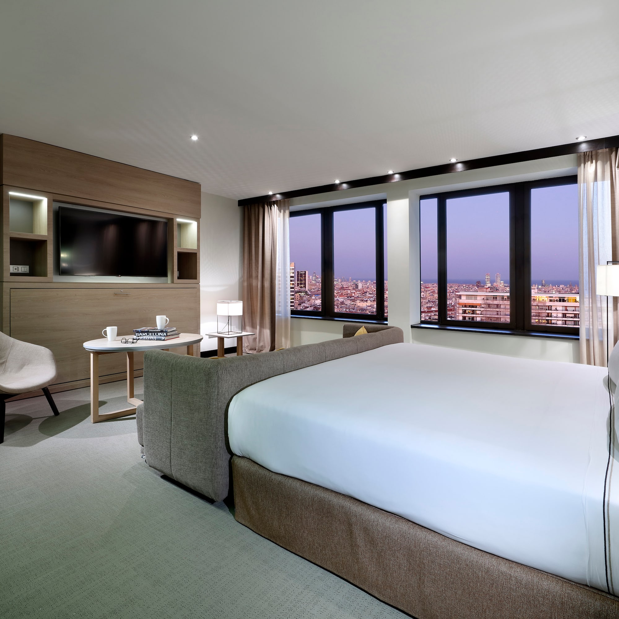 Modern luxury hotel room with city view, king bed, and contemporary decor.