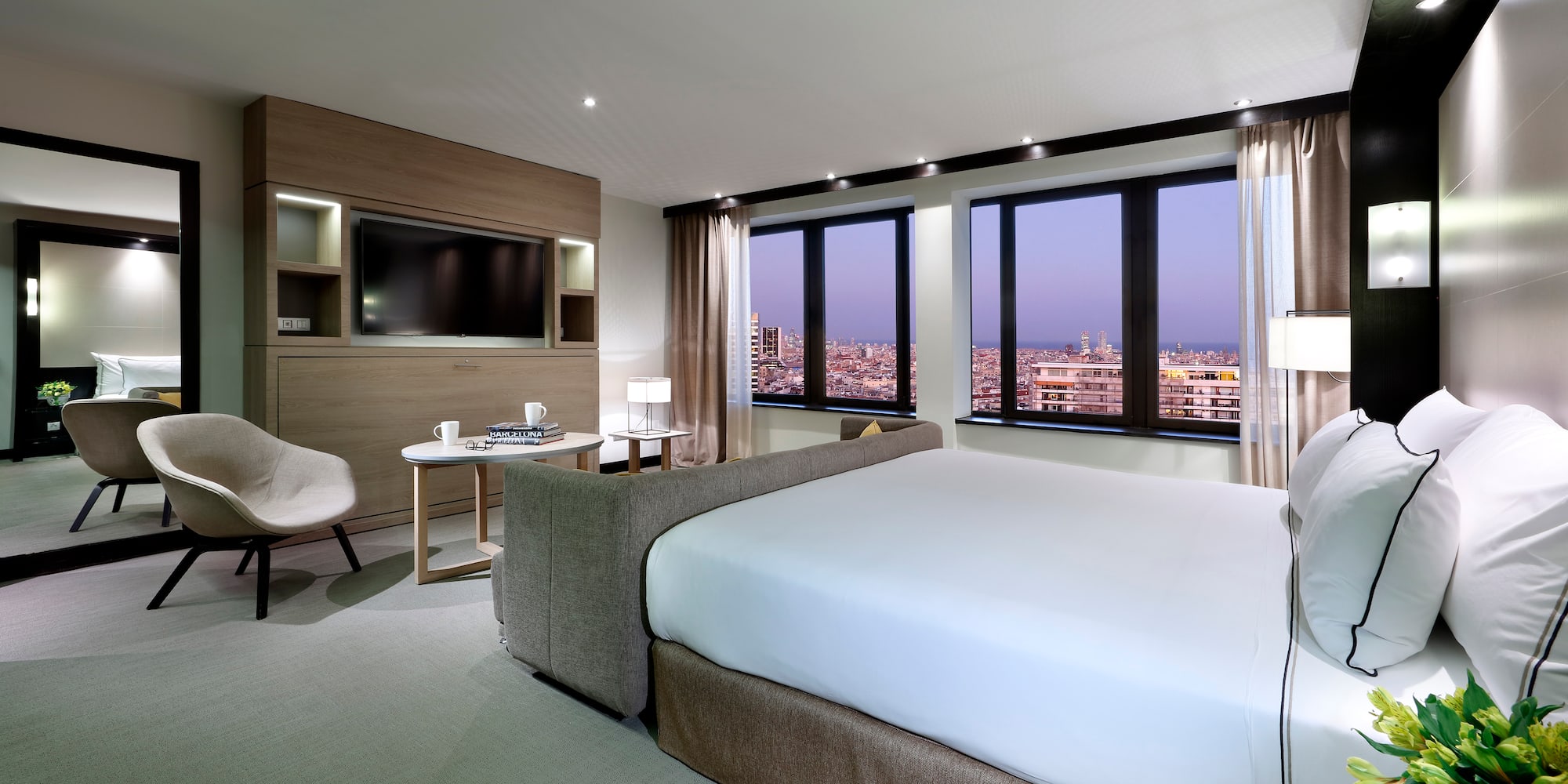 Modern luxury hotel room with city view, king bed, and contemporary decor.