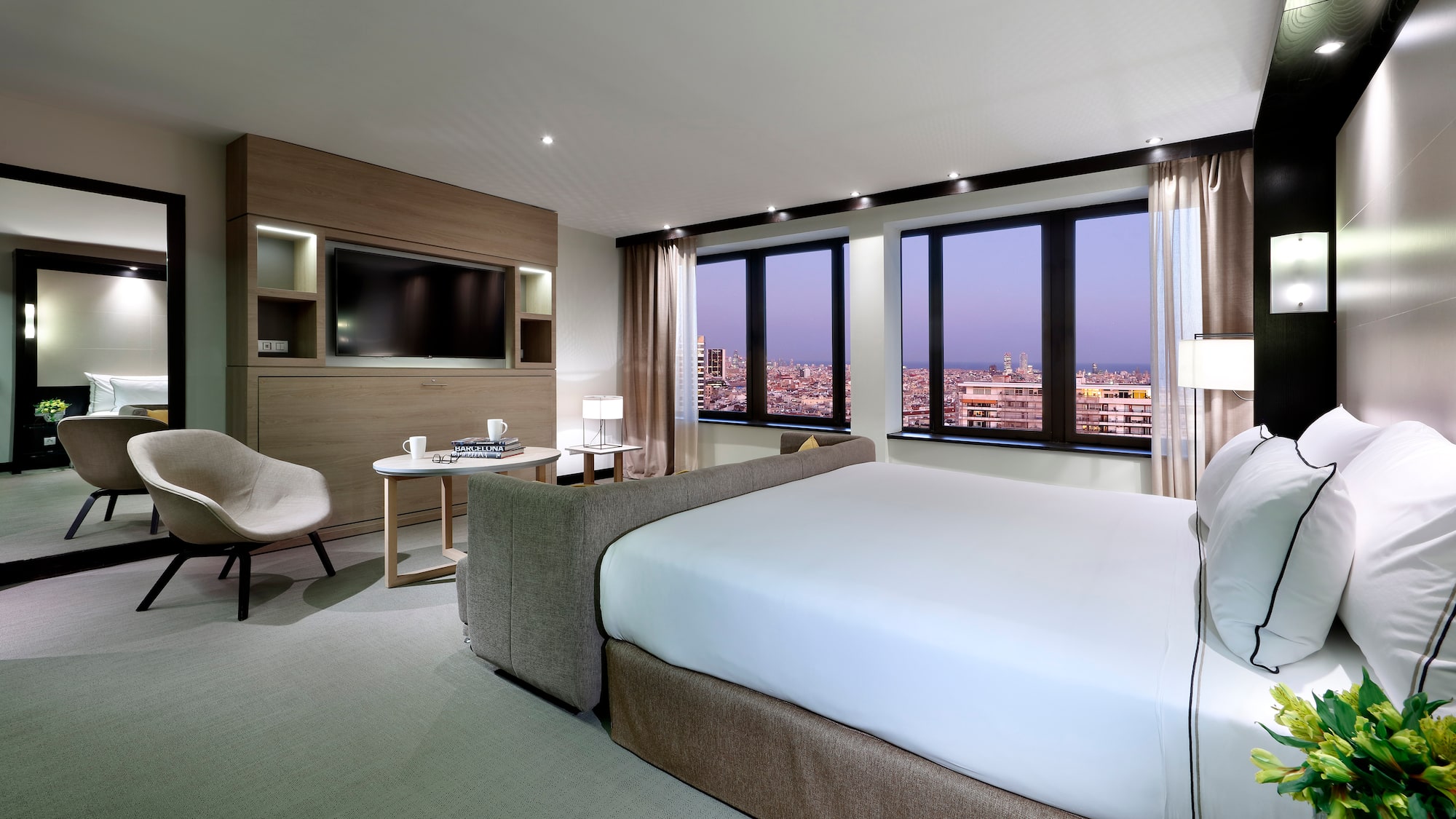 Modern luxury hotel room with city view, king bed, and contemporary decor.