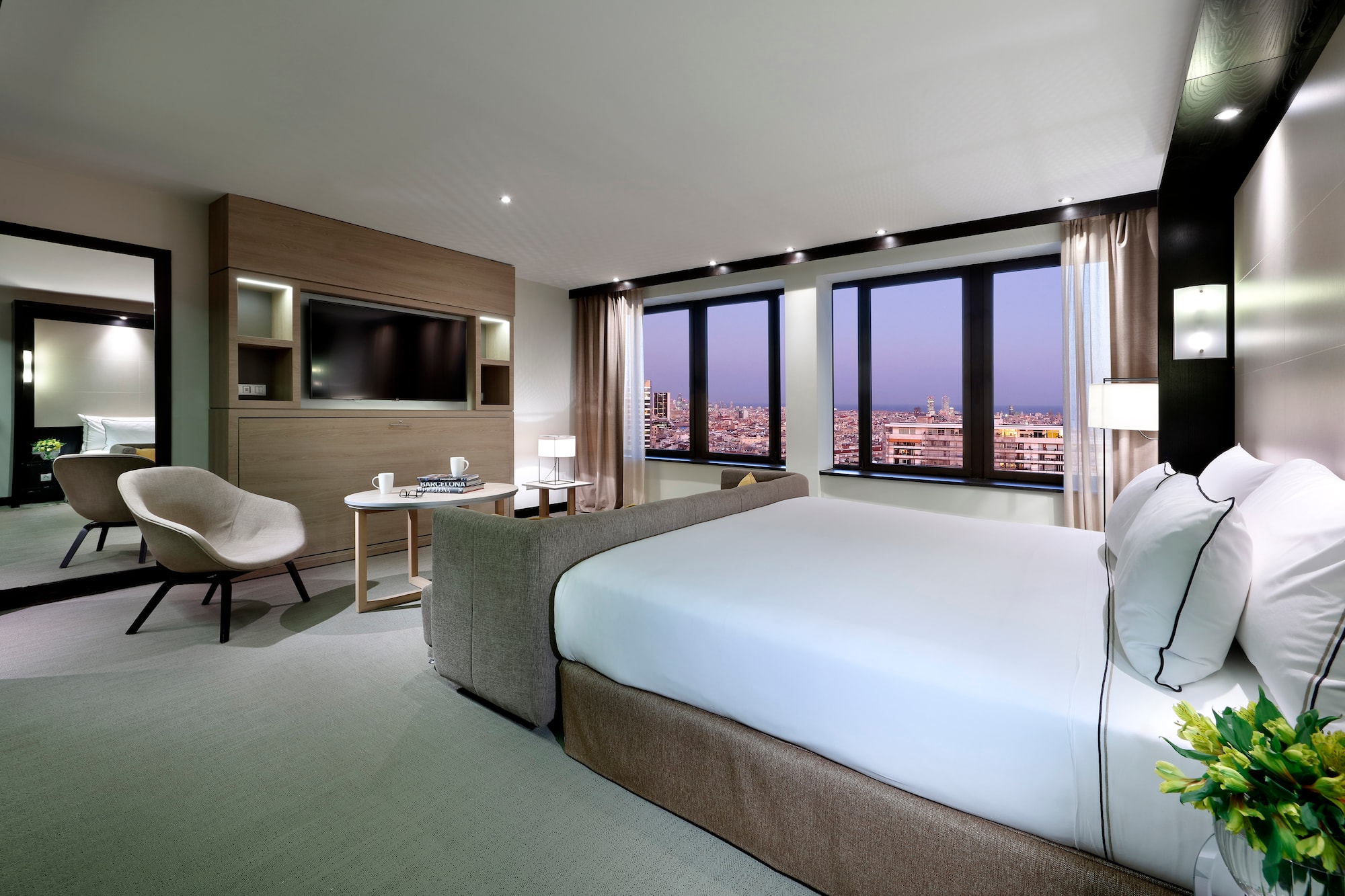 Modern luxury hotel room with city view, king bed, and contemporary decor.