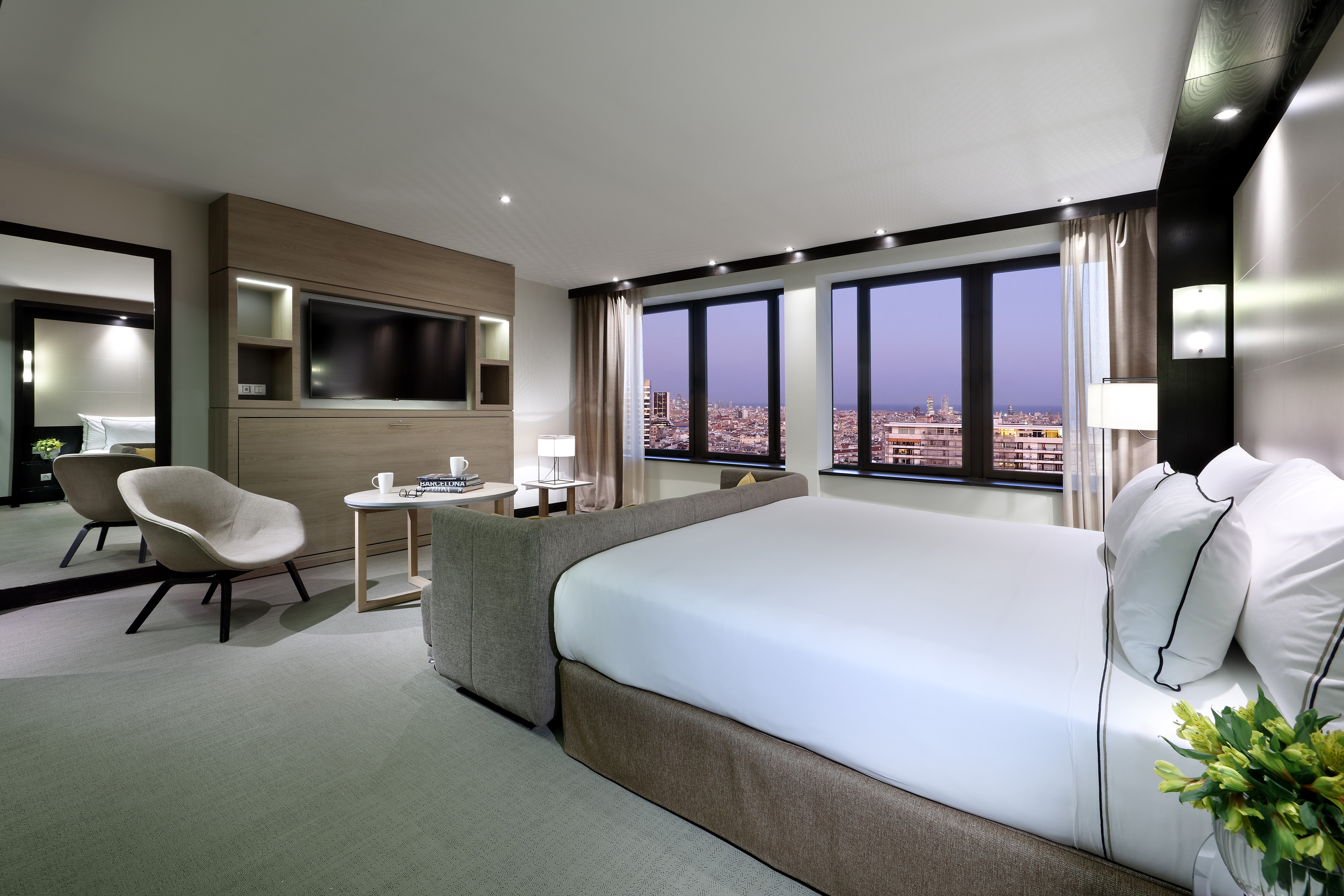 Modern luxury hotel room with city view, king bed, and contemporary decor.