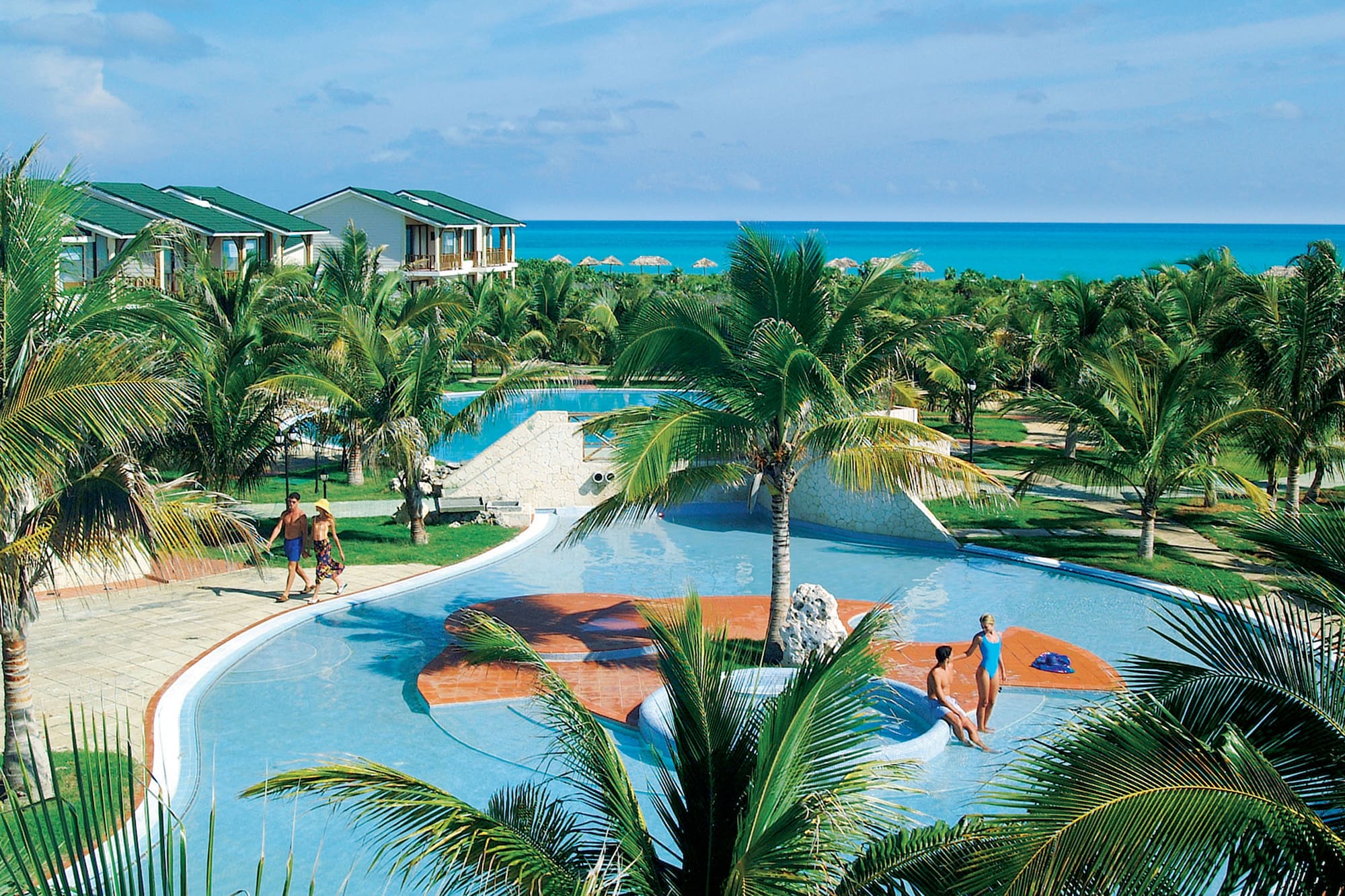 a group of people in a pool with Cayo Coco in the background