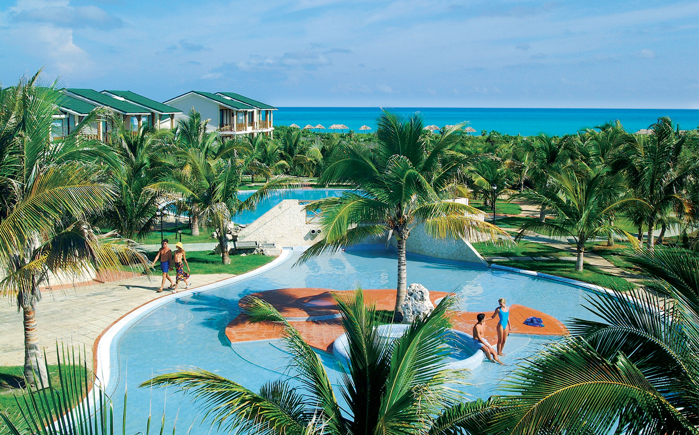 a group of people in a pool with Cayo Coco in the background