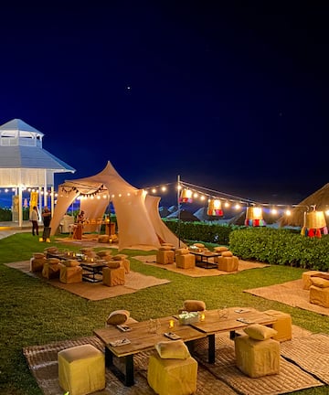 a group of tables and chairs in a lawn with lights and a gazebo