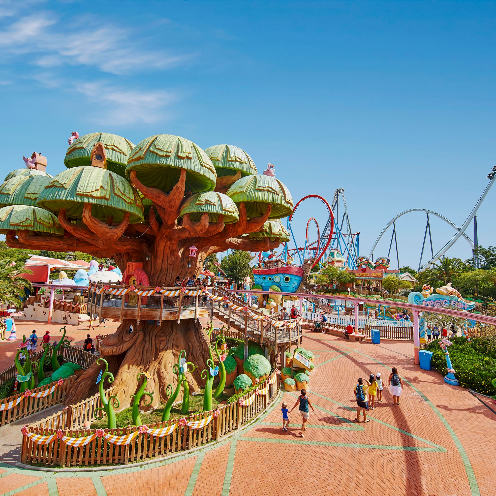 a large tree with green roofs and people walking around
