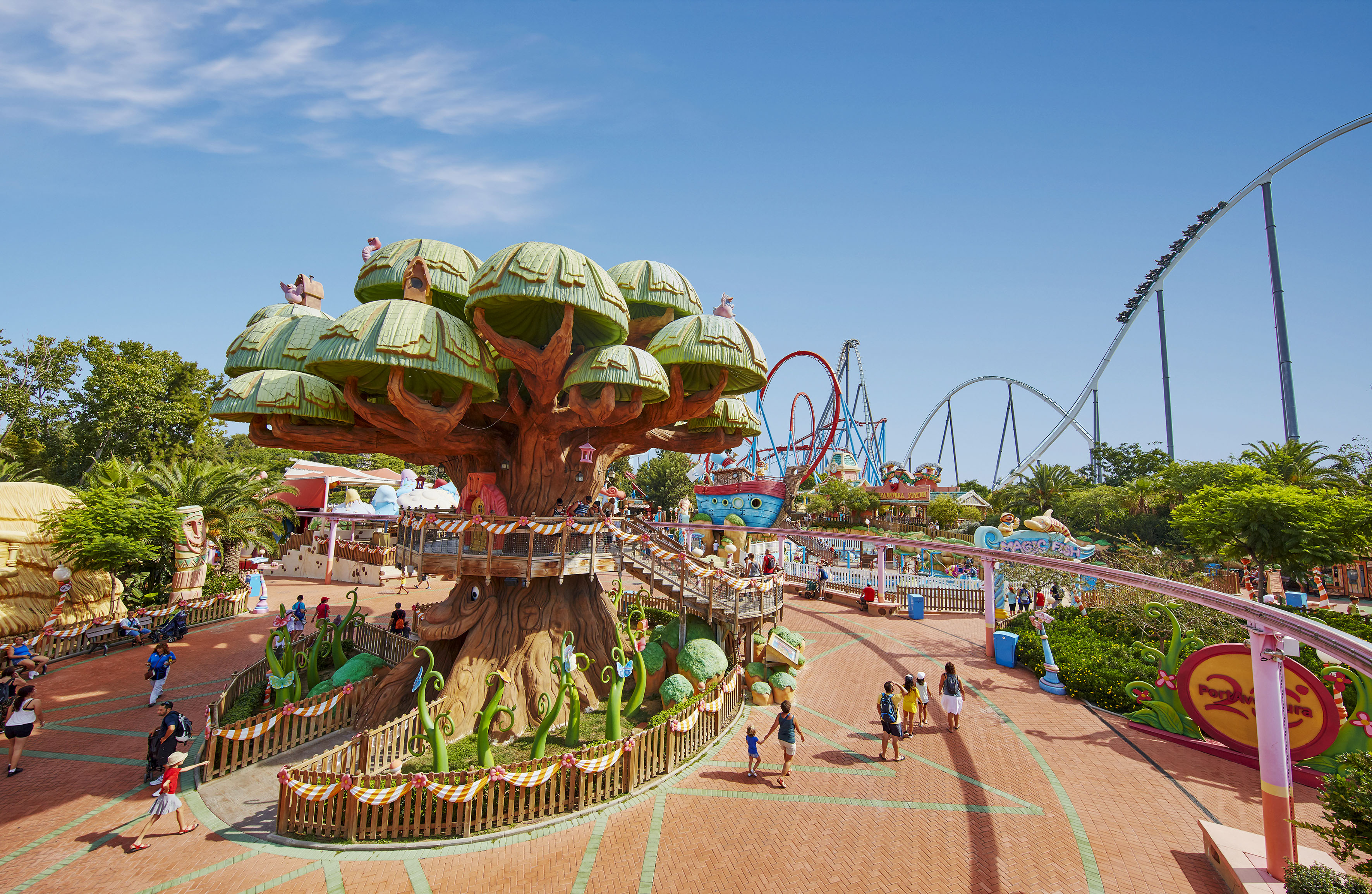 a large tree with green roofs and people walking around