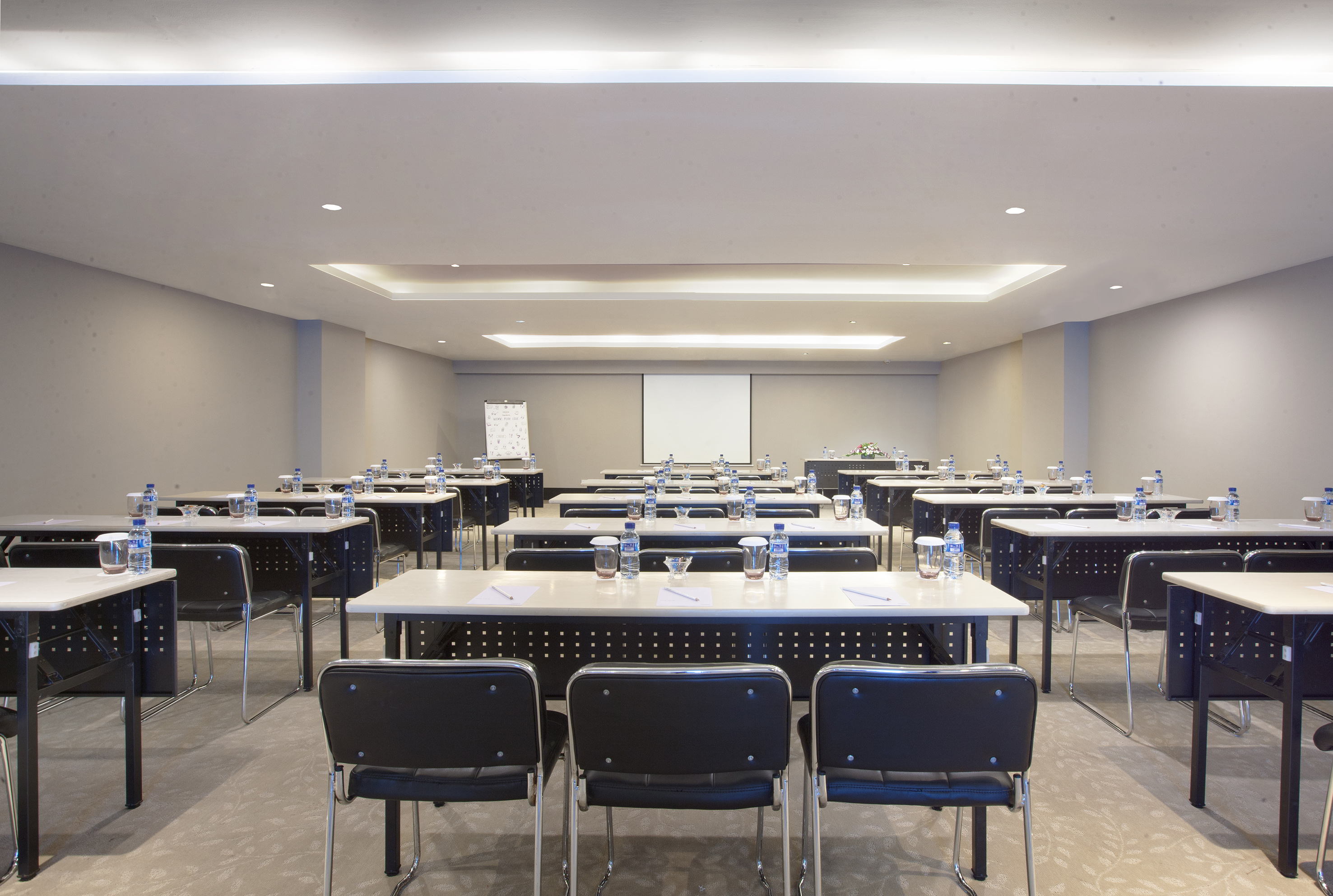Empty training room with classroom seating, projector screen, and flipchart.