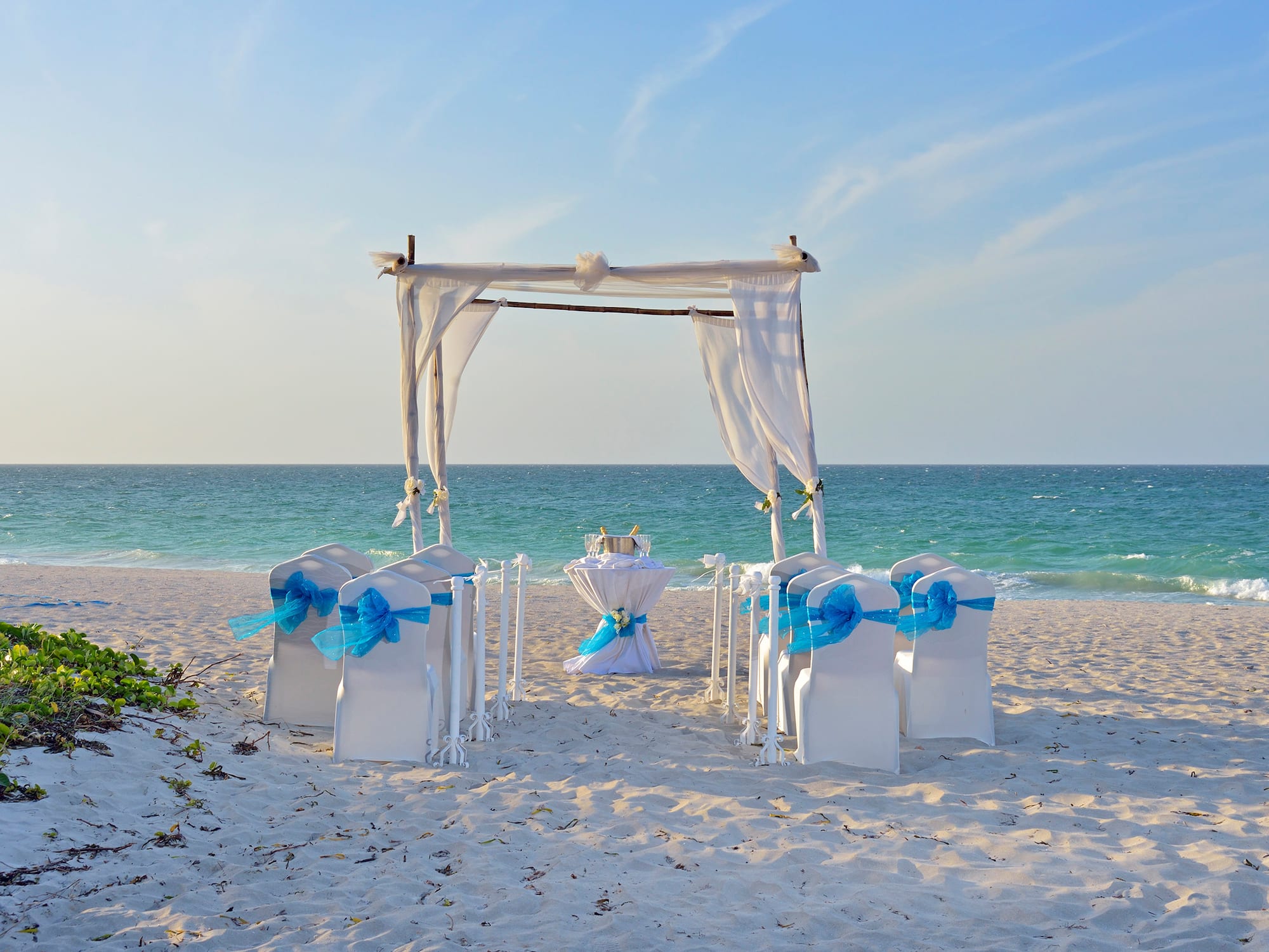 a beach setting with chairs and a table with a table set up