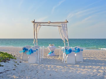 a beach setting with chairs and a table with a table set up