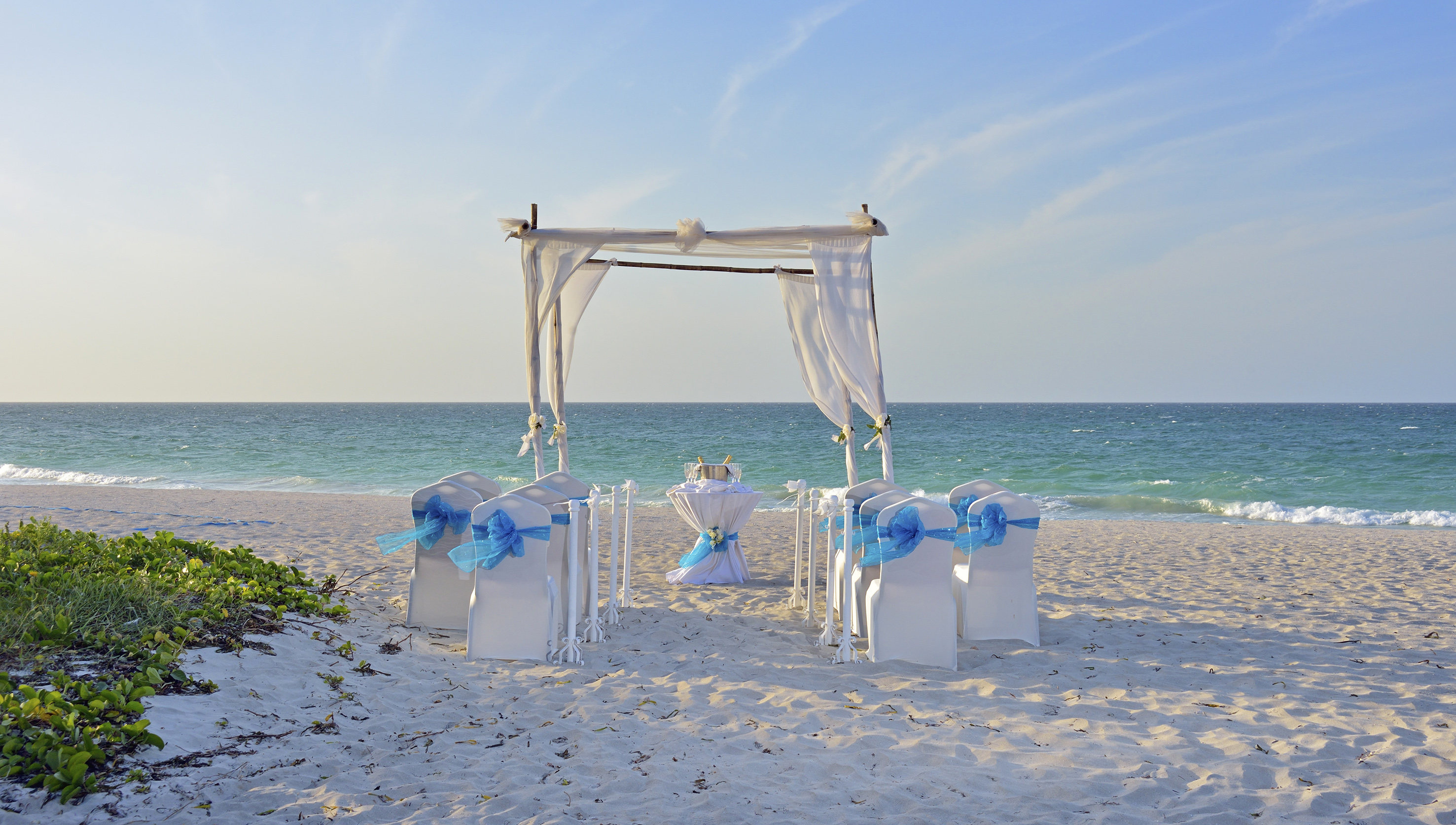 a beach setting with chairs and a table with a table set up