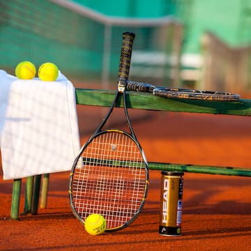 a tennis racket and balls on a bench