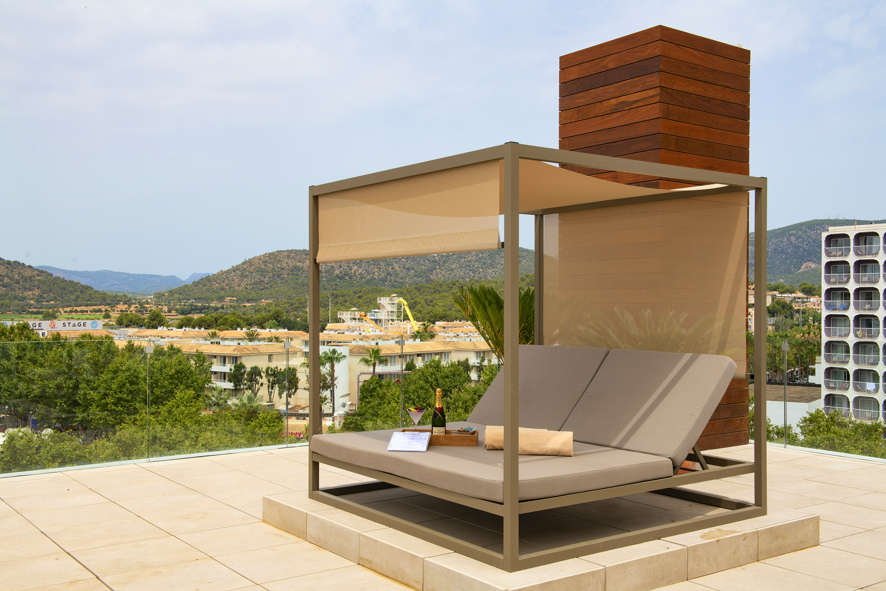 Resort daybed with champagne on terrace, mountain and water park view.
