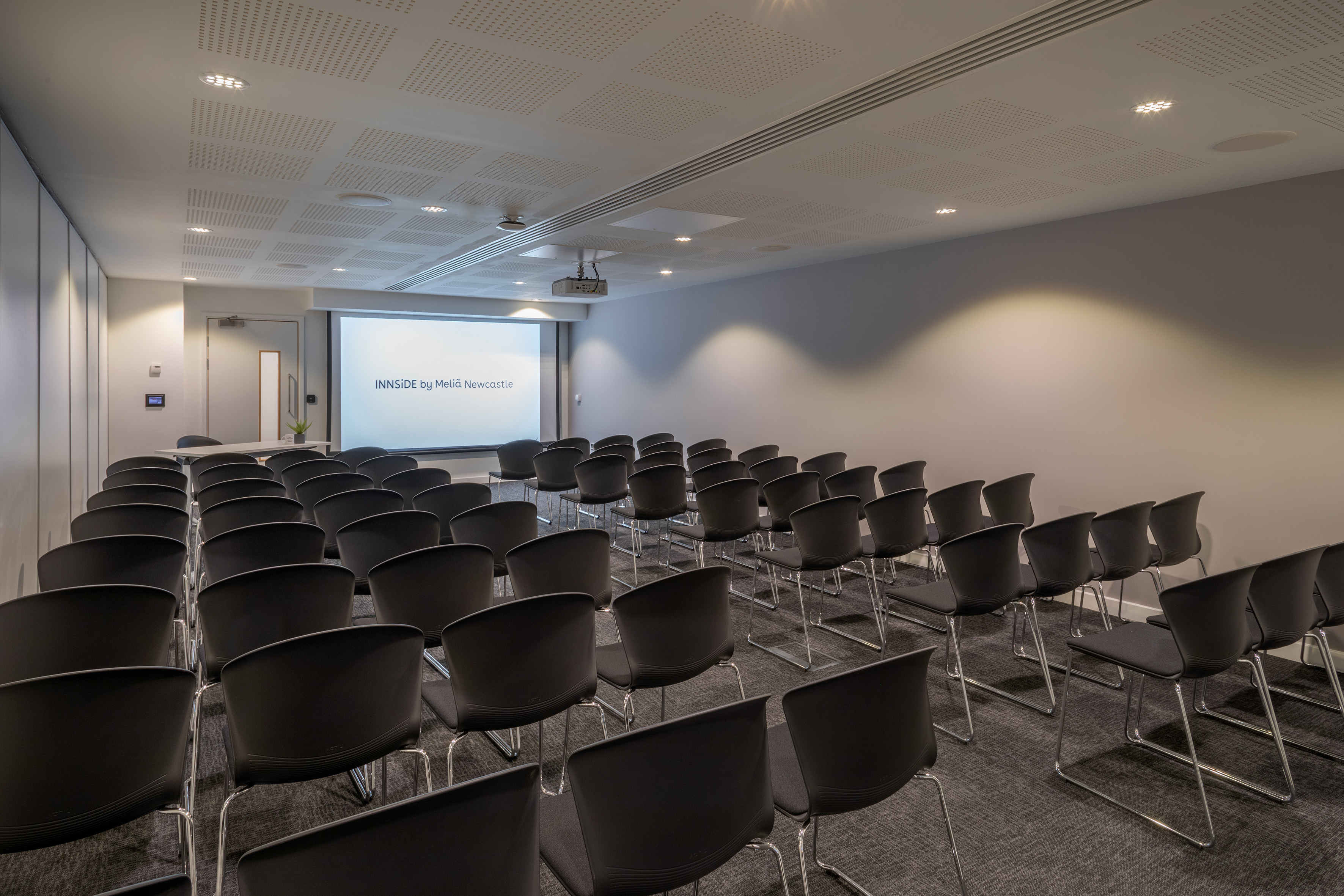 INNSiDE Newcastle modern meeting room with rows of chairs and projector screen.
