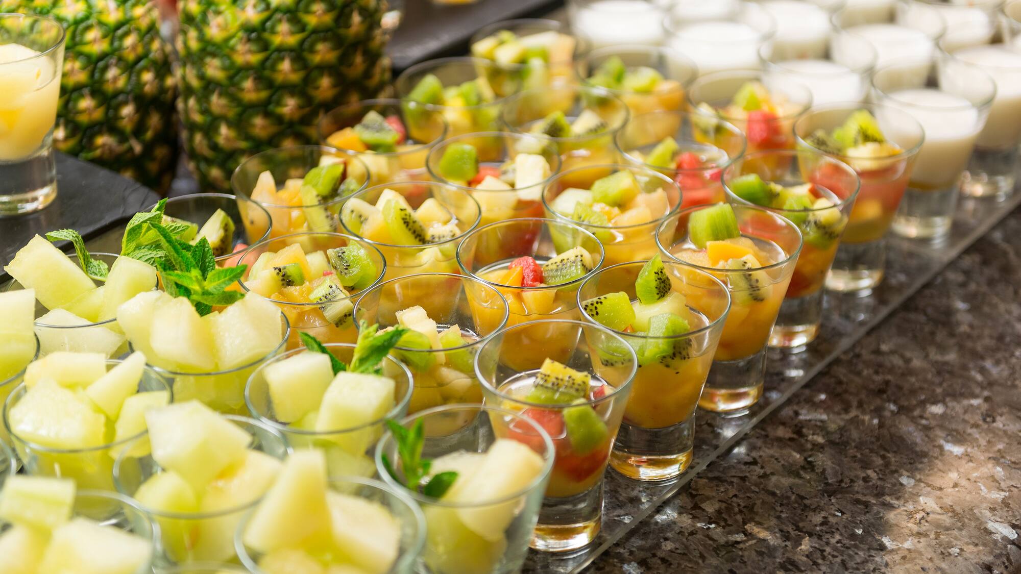 a group of glasses of fruit in a row