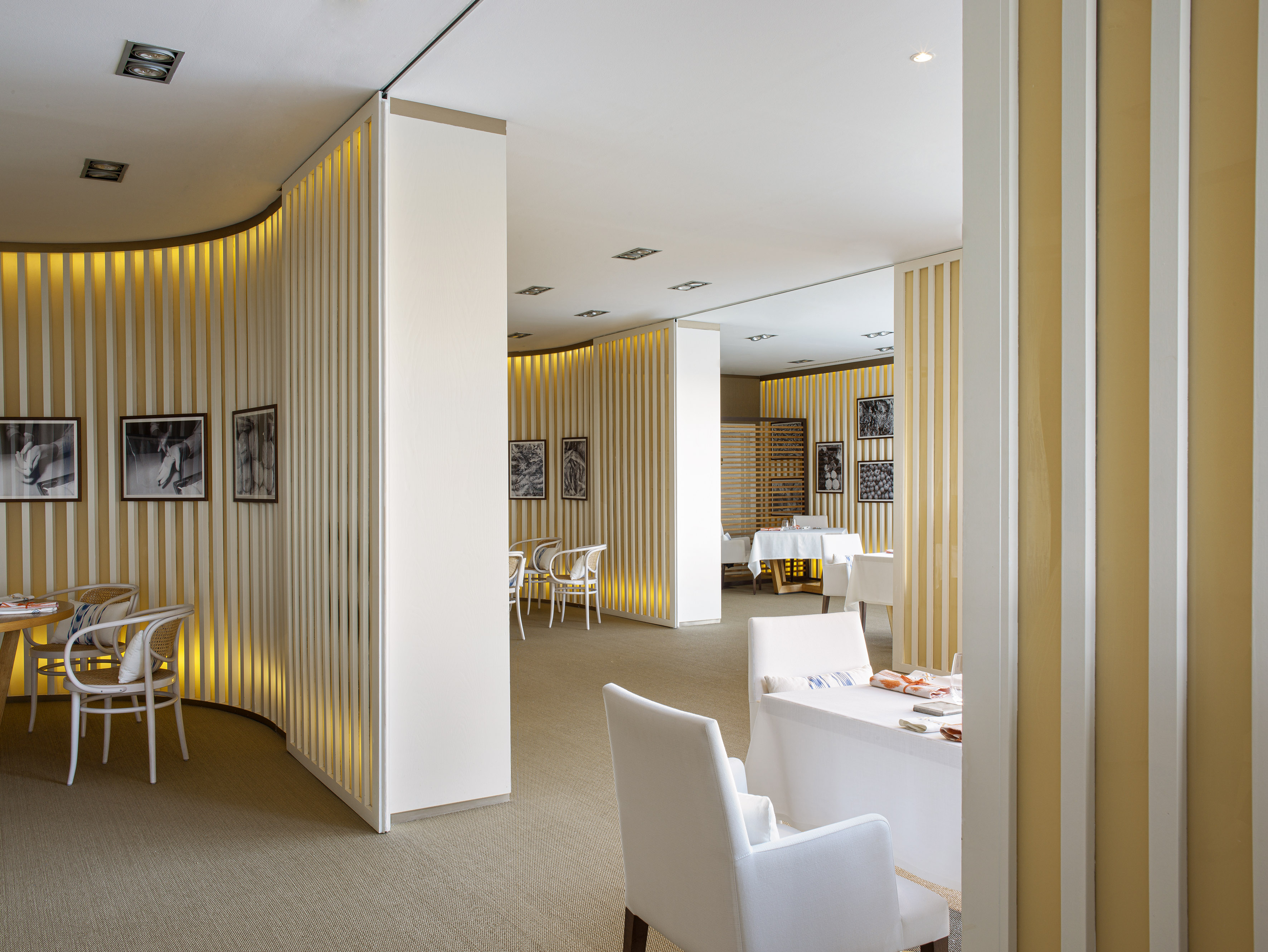 Modern restaurant interior, warm backlit slatted dividers, dining tables.
