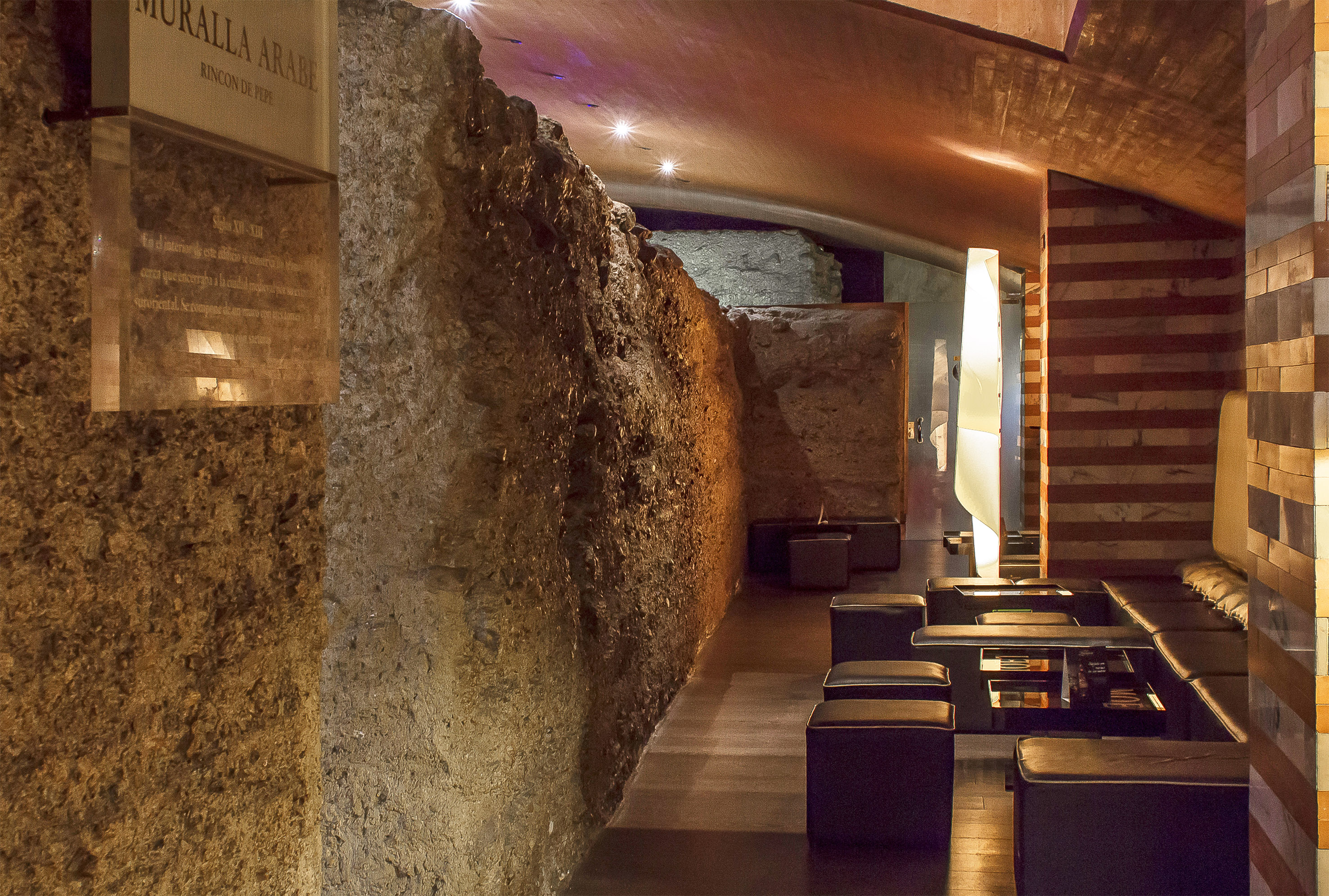 a stone wall with tables and chairs
