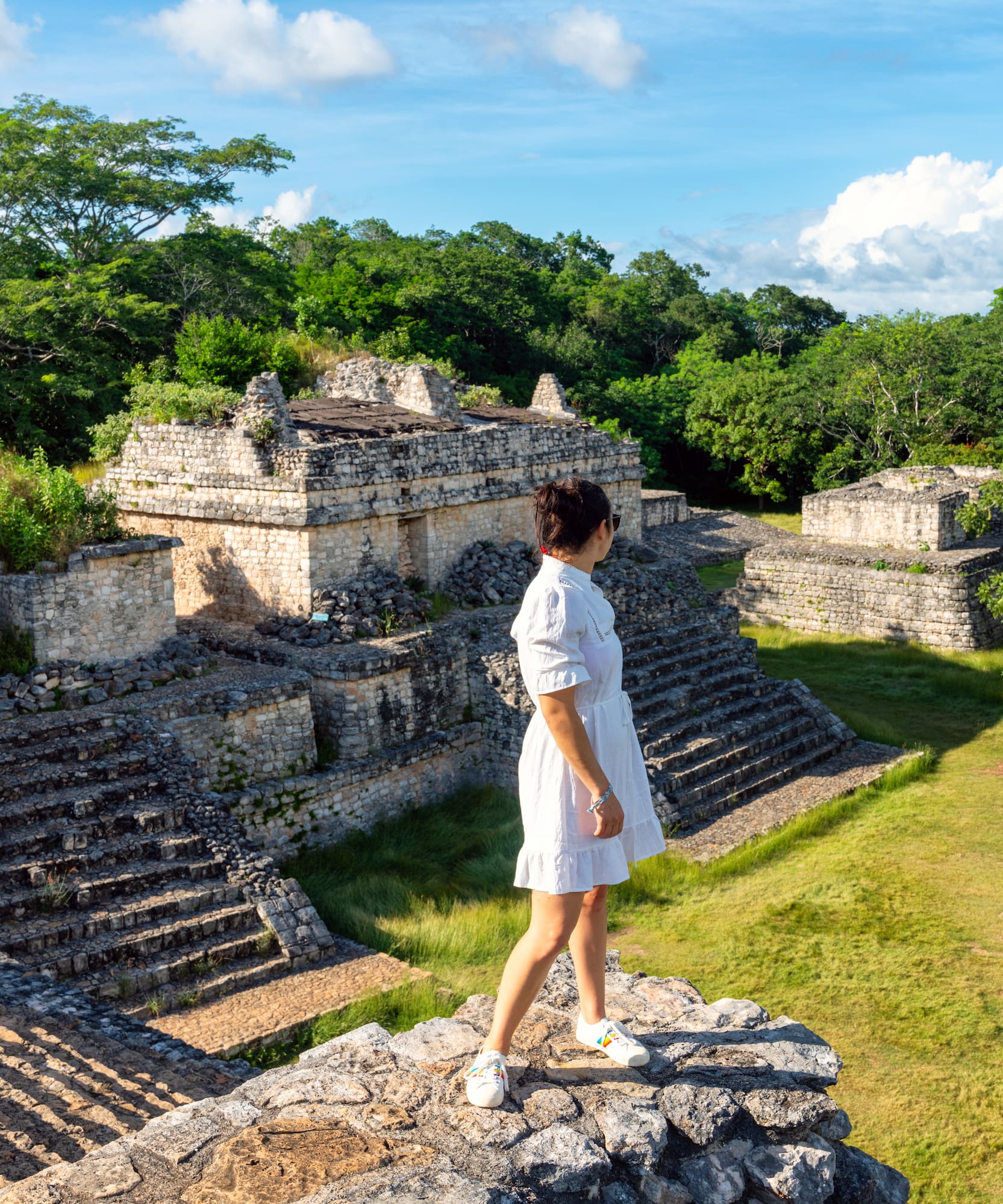 Mujer explorando sitio arqueológico maya, rodeado de selva.