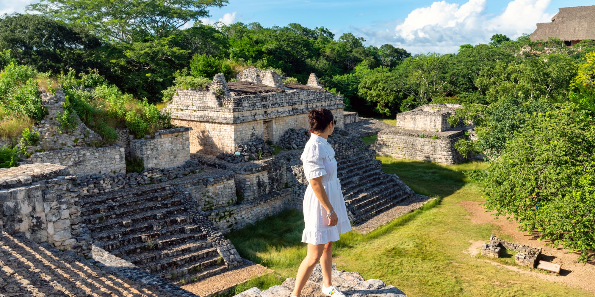 a woman standing on a rock ledge in front of a stone building