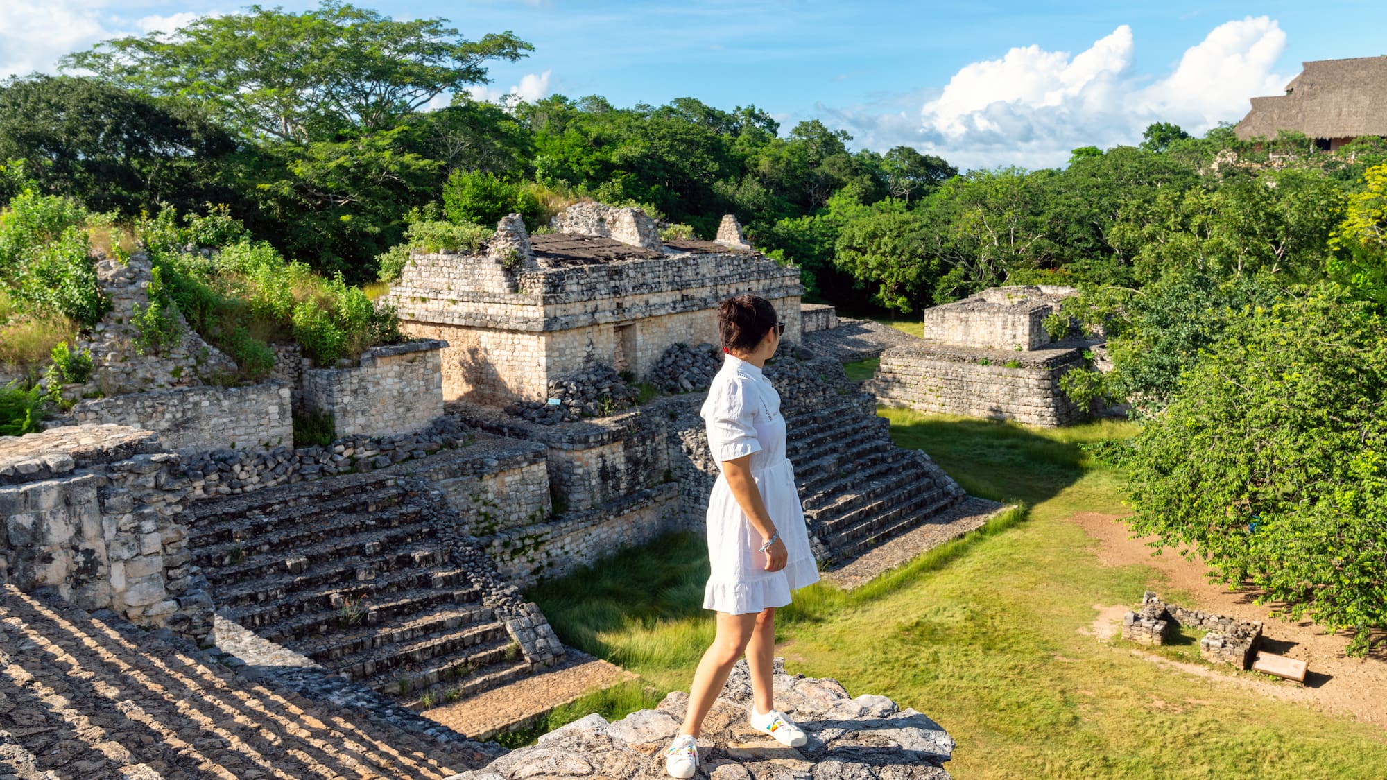 a woman standing on a rock ledge in front of a stone building