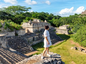 a woman standing on a rock ledge in front of a stone building
