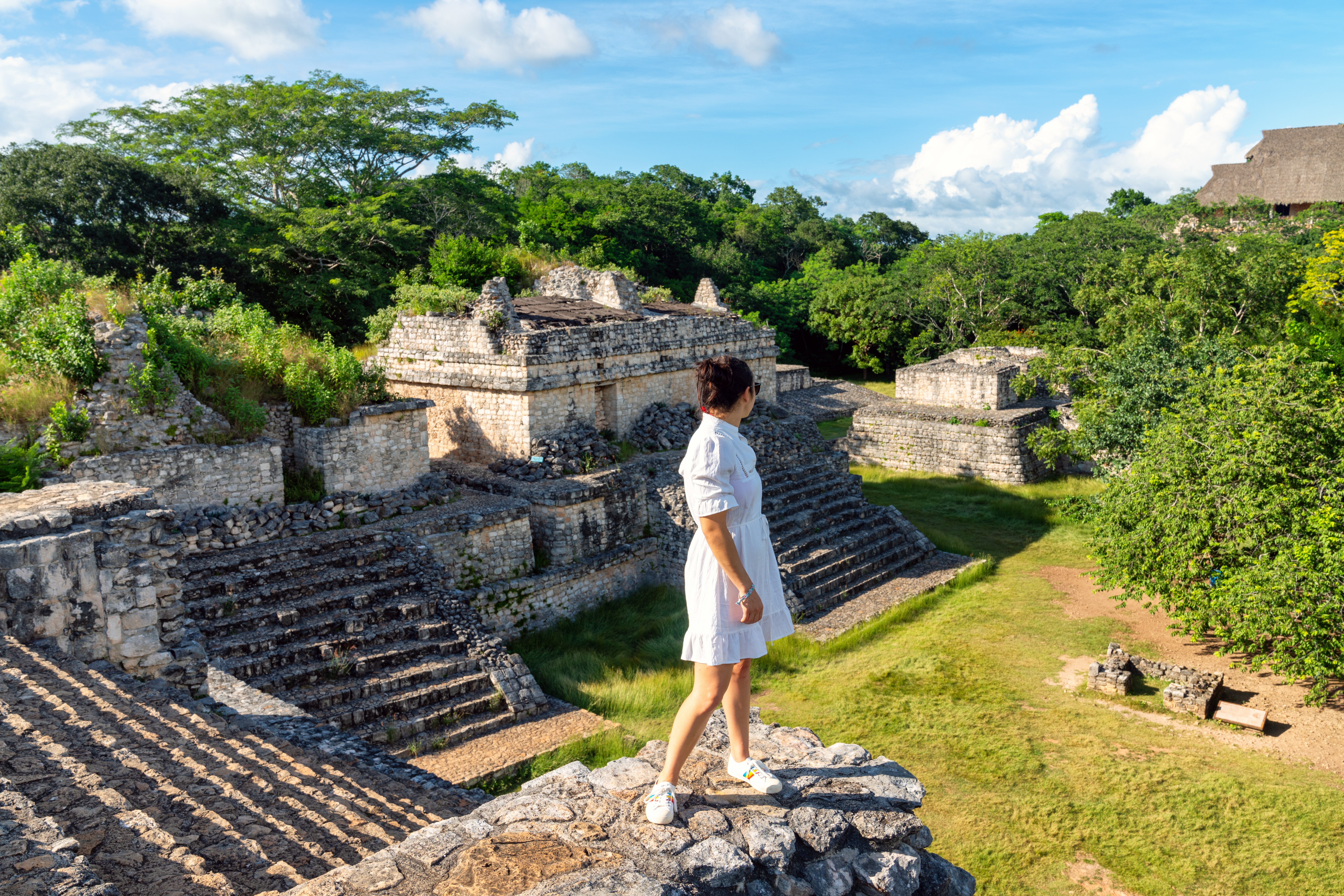 Mujer explorando sitio arqueológico maya, rodeado de selva.