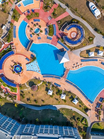 an aerial view of a resort with a pool and a building