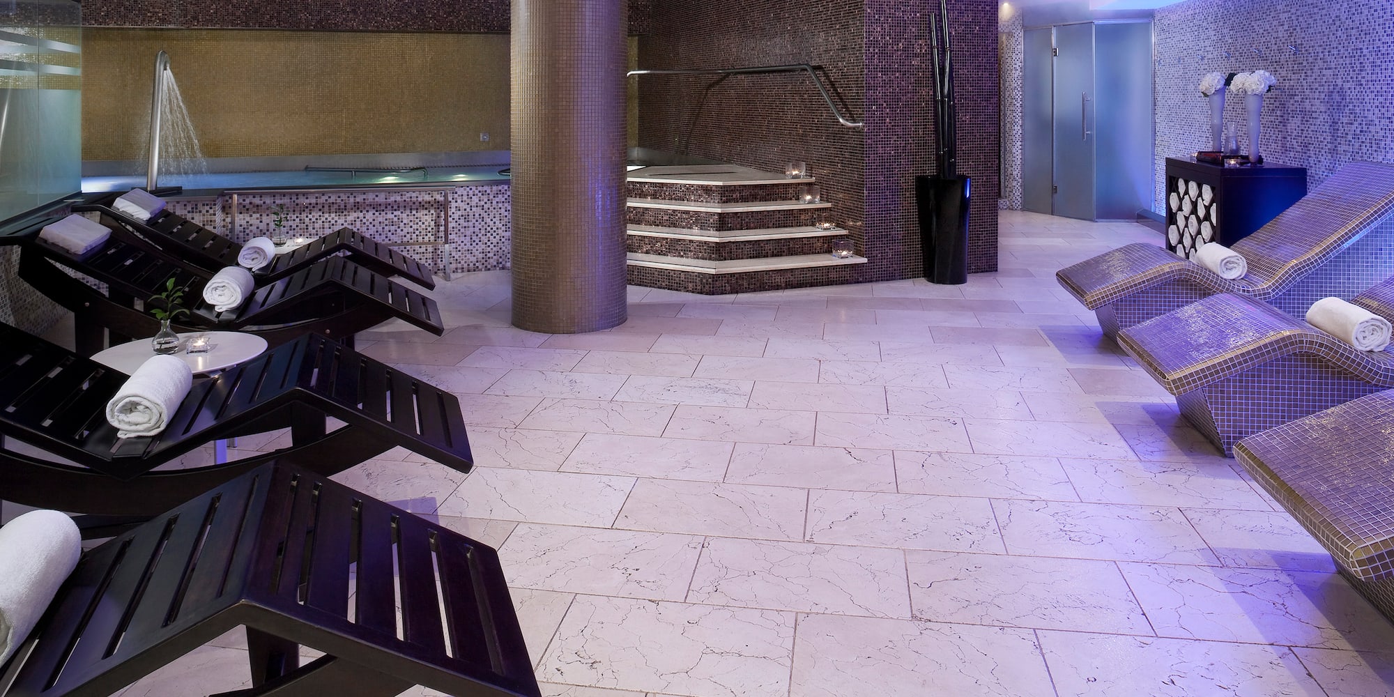 a room with a large round pool and a large staircase