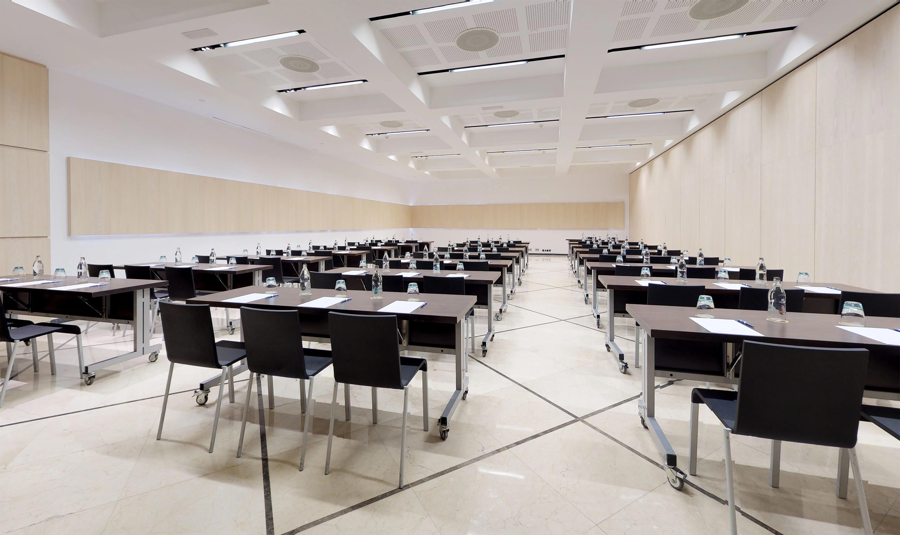 Modern empty conference room with tables, chairs, water, light wood walls.