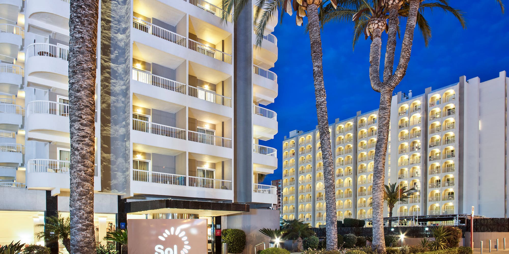 a building with palm trees and a sign