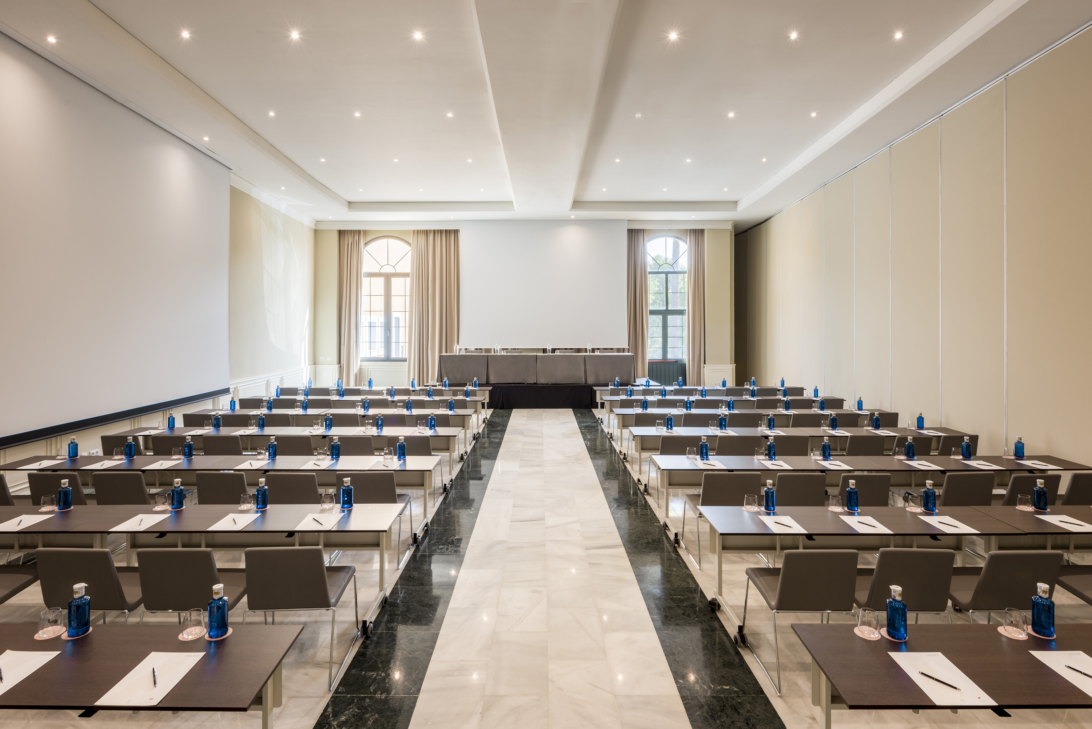 Spacious conference room, classroom setup, projection screen, tables, and water.