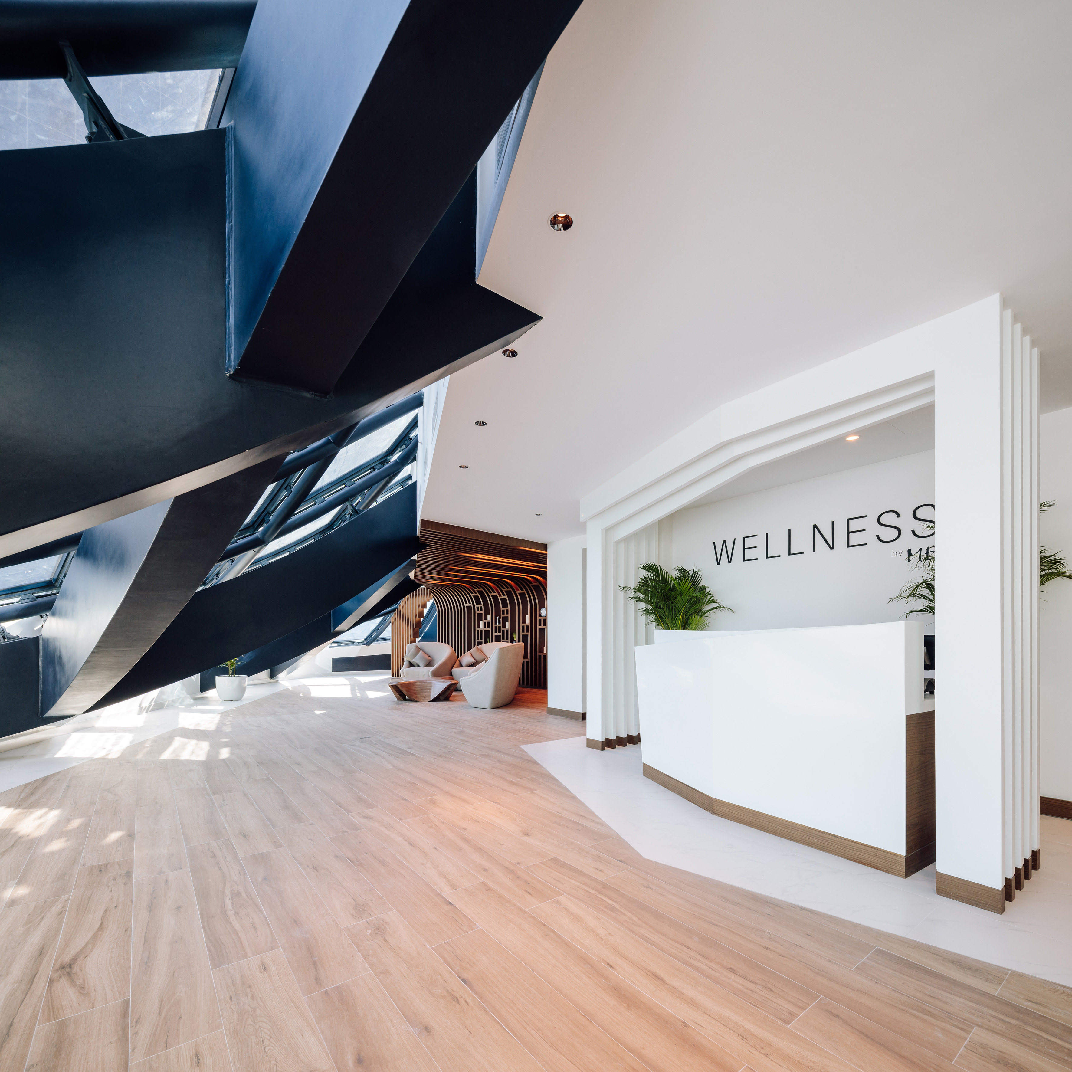 Wellness reception with white desk, 'WELLNESS' sign, wood floor, dark angular design.