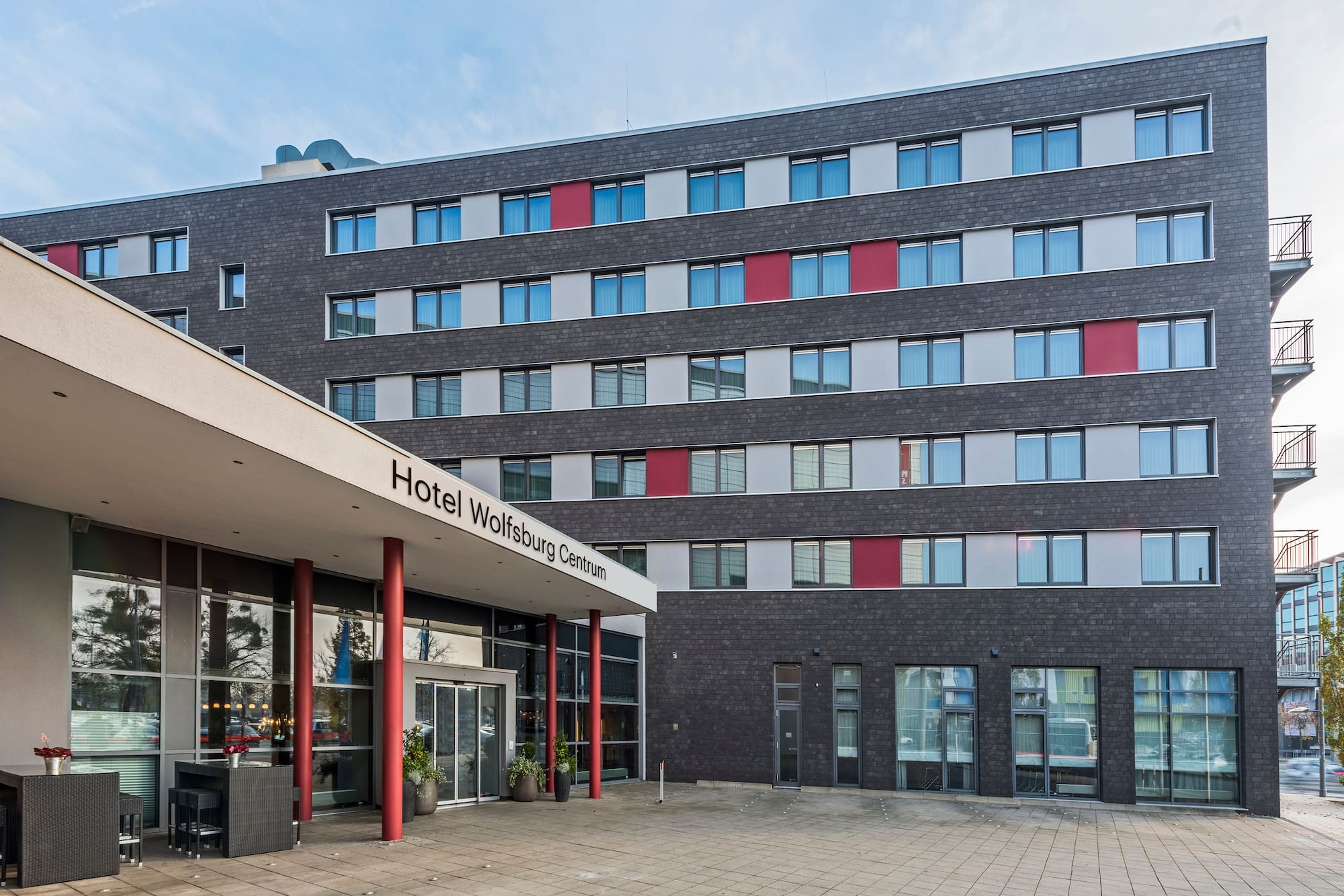 Hotel Wolfsburg Centrum: Modern exterior, dark facade, red accents, entrance.